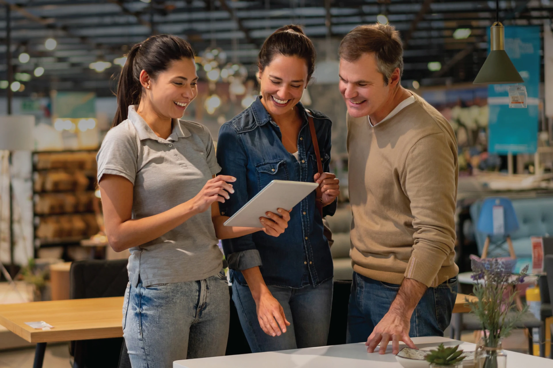 Three professionals discussing insights using a tablet in a retail space.