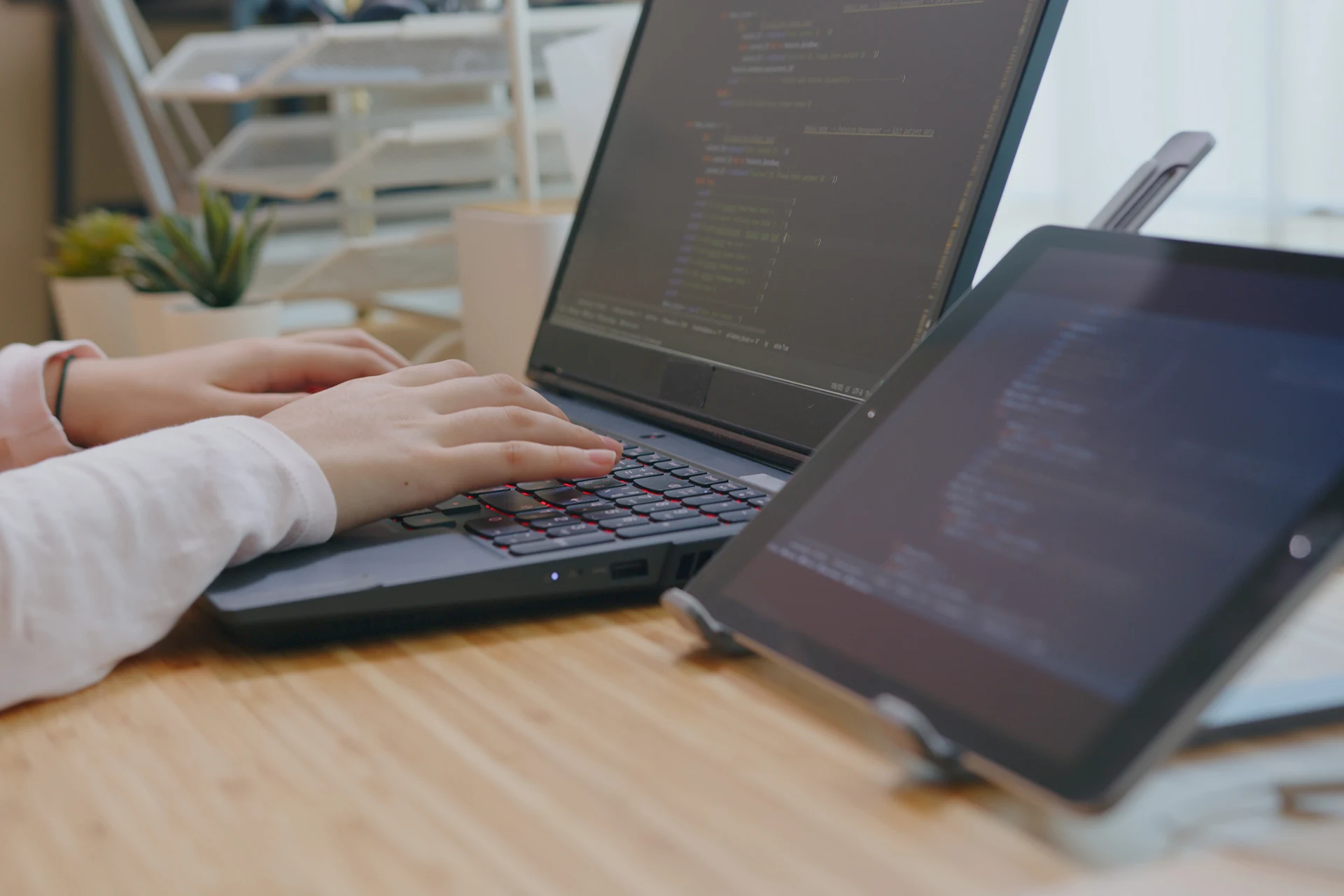 Hands typing on a laptop while working on a coding project