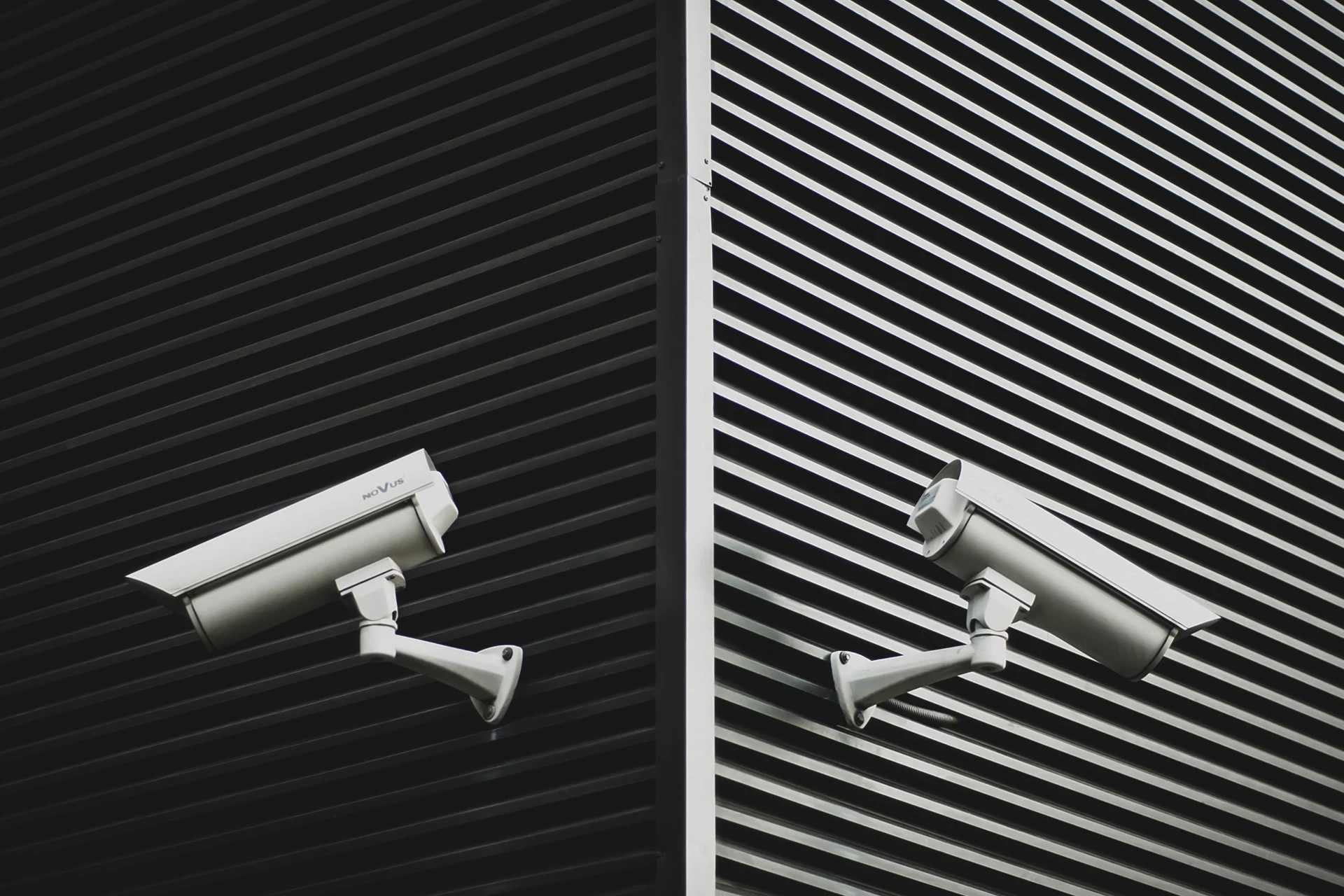 Two CCTV cameras mounted on a wall in a retail environment