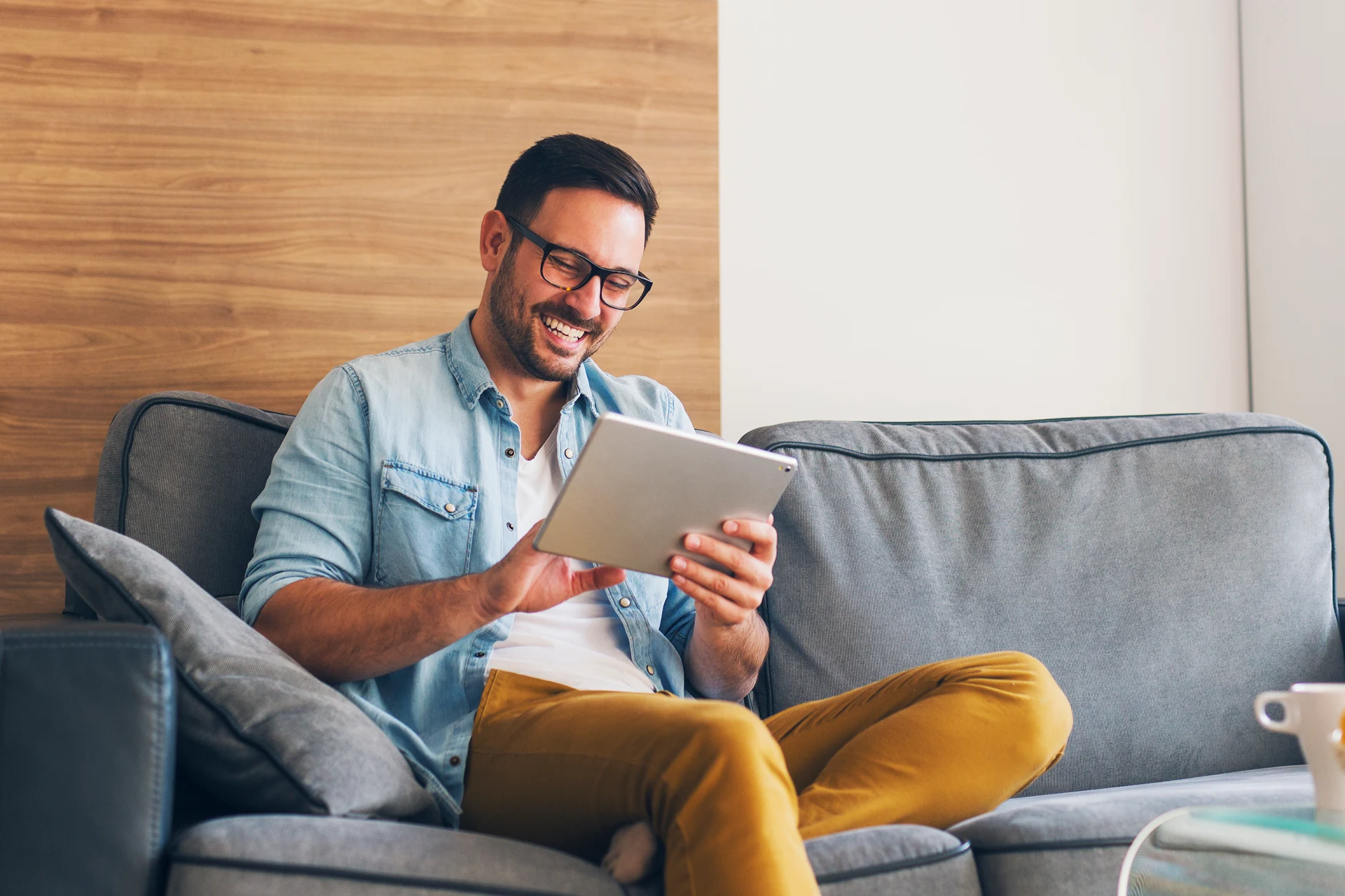 Person sitting on a couch using a tablet in a casual setting.