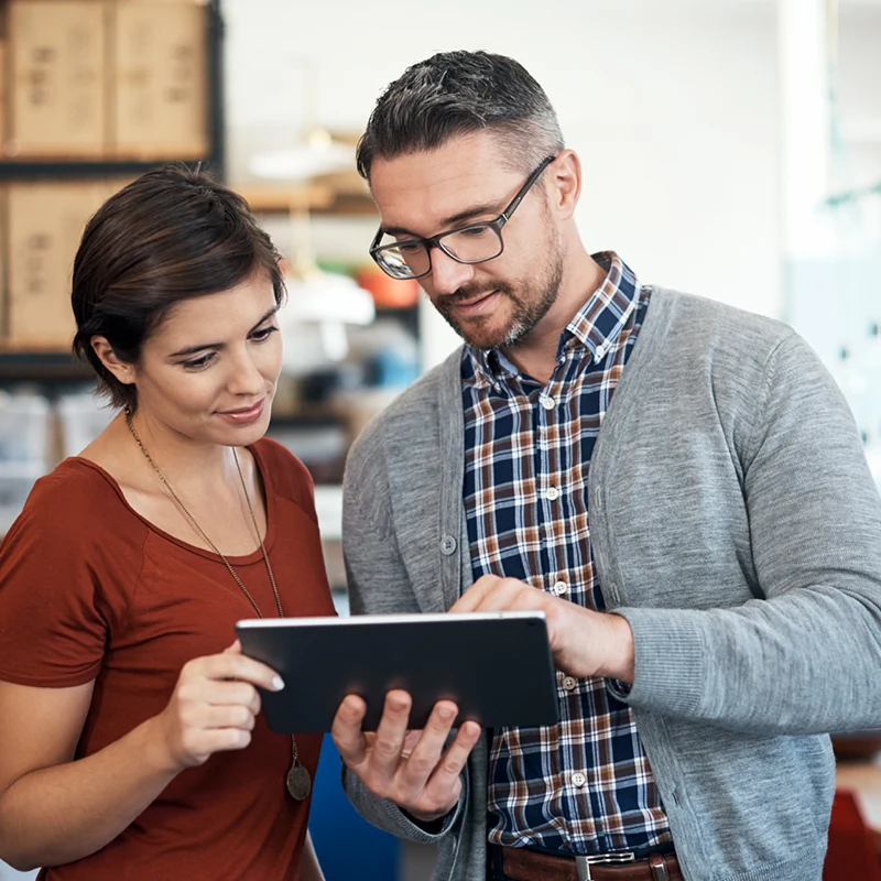Two professionals discussing e-commerce solutions on a tablet.
