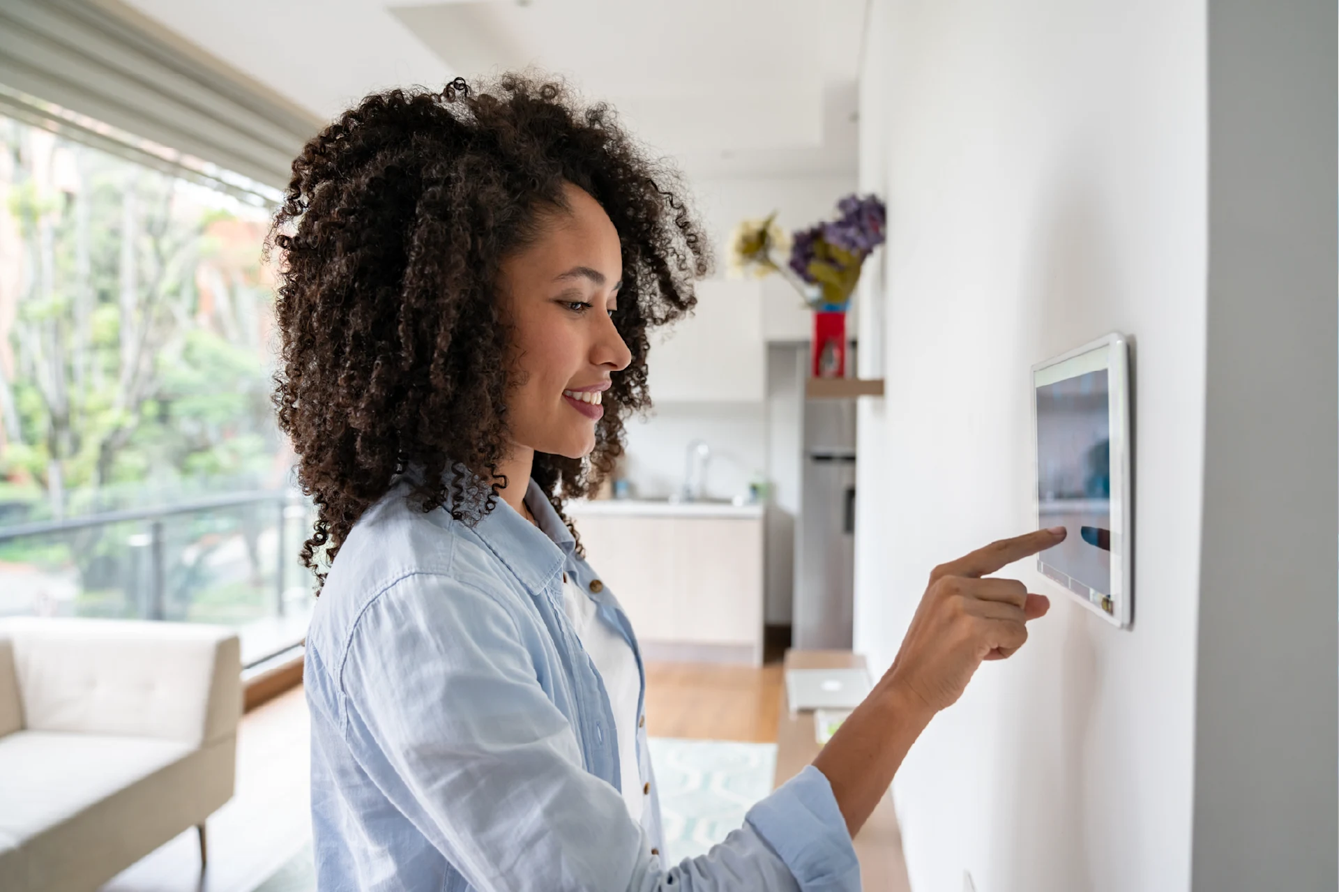 Person interacting with a touchscreen device in a modern home setting