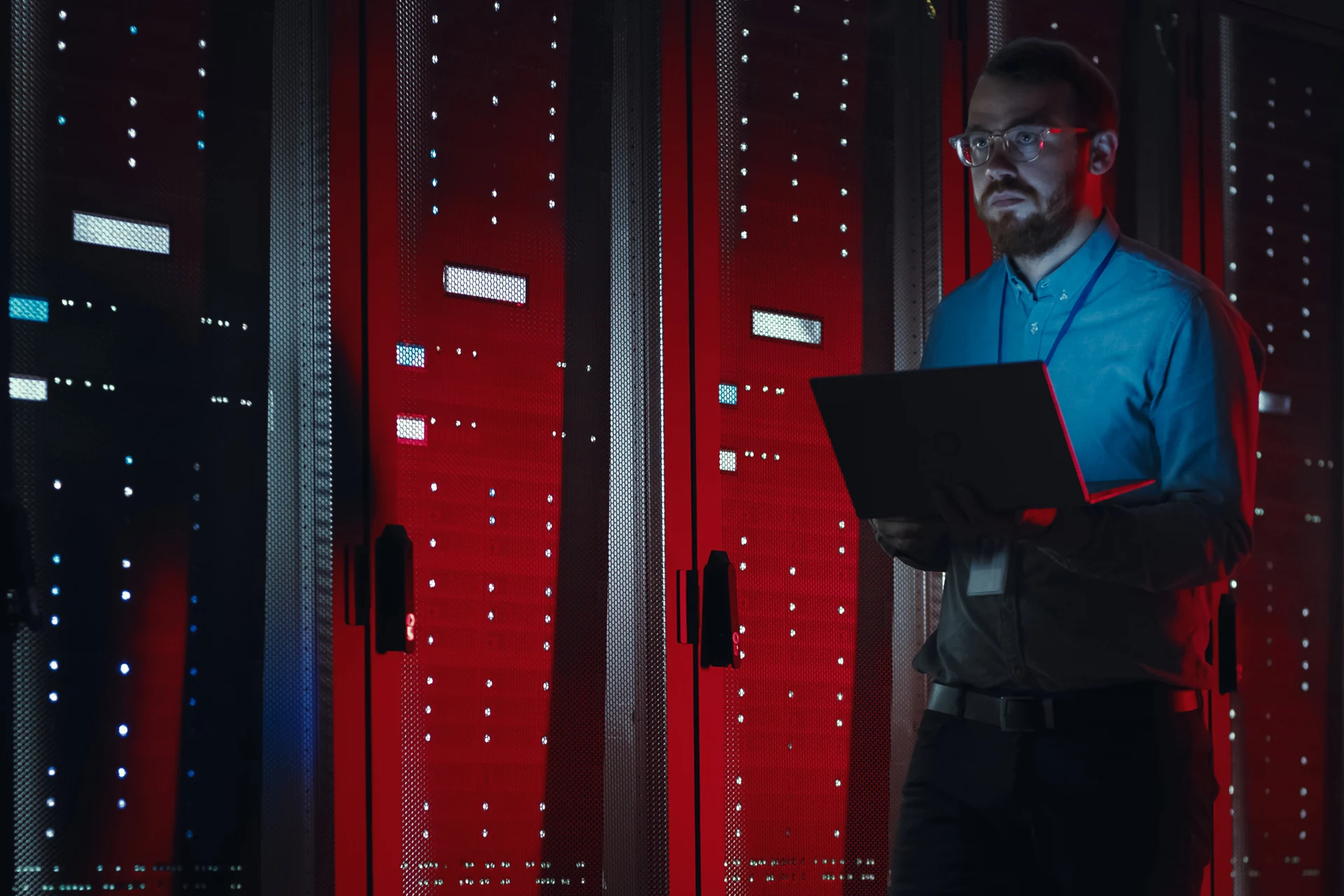 Professional reviewing data on a laptop in a server room setting
