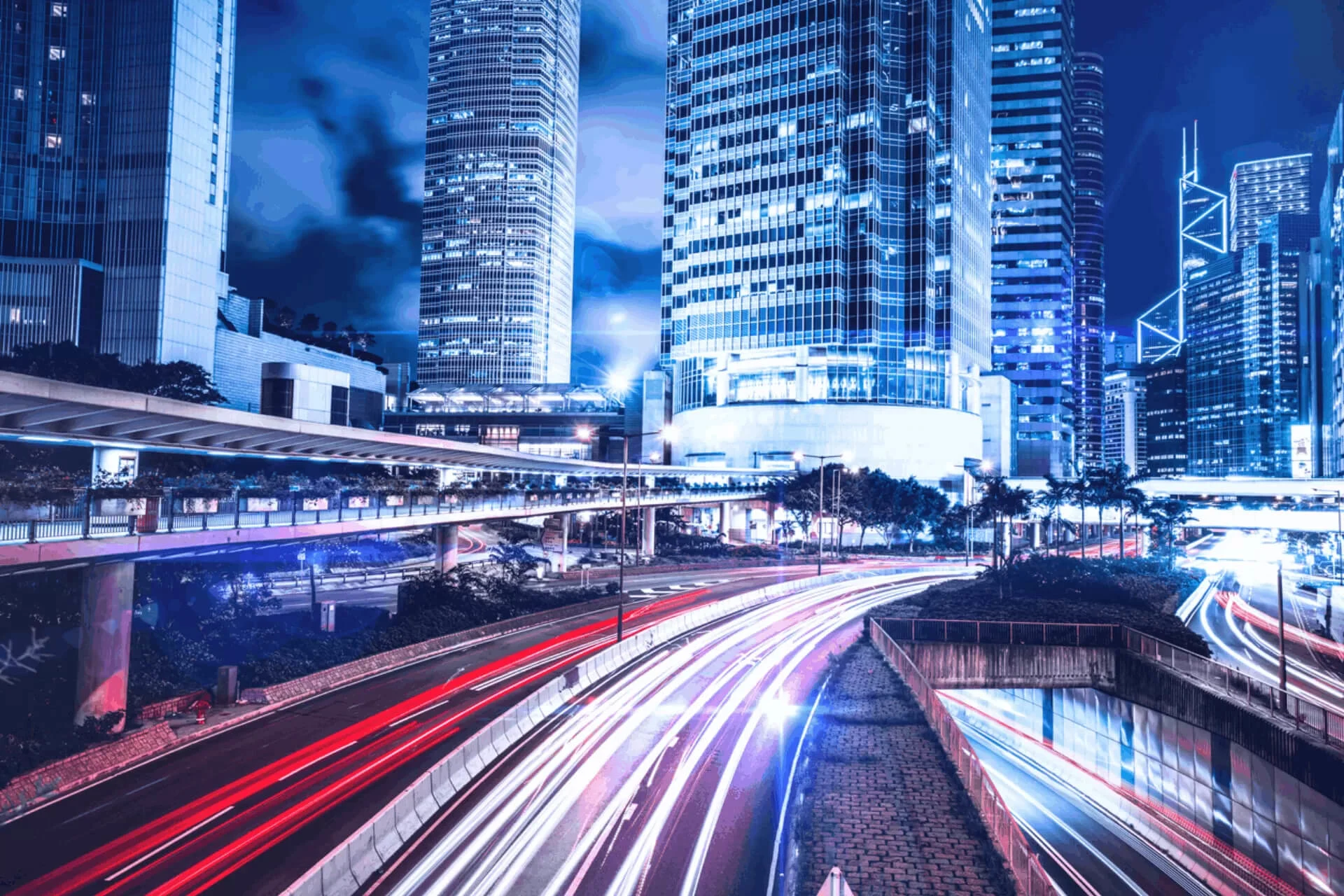 City skyline at night with light trails from moving vehicles.