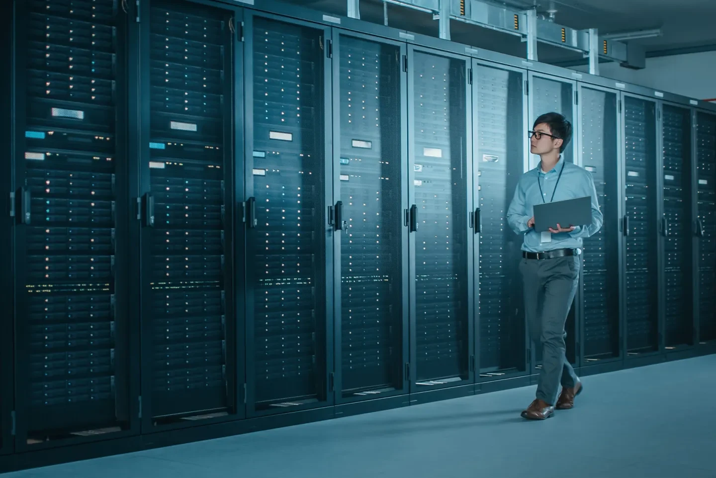 Professional walking past server racks in a data center environment