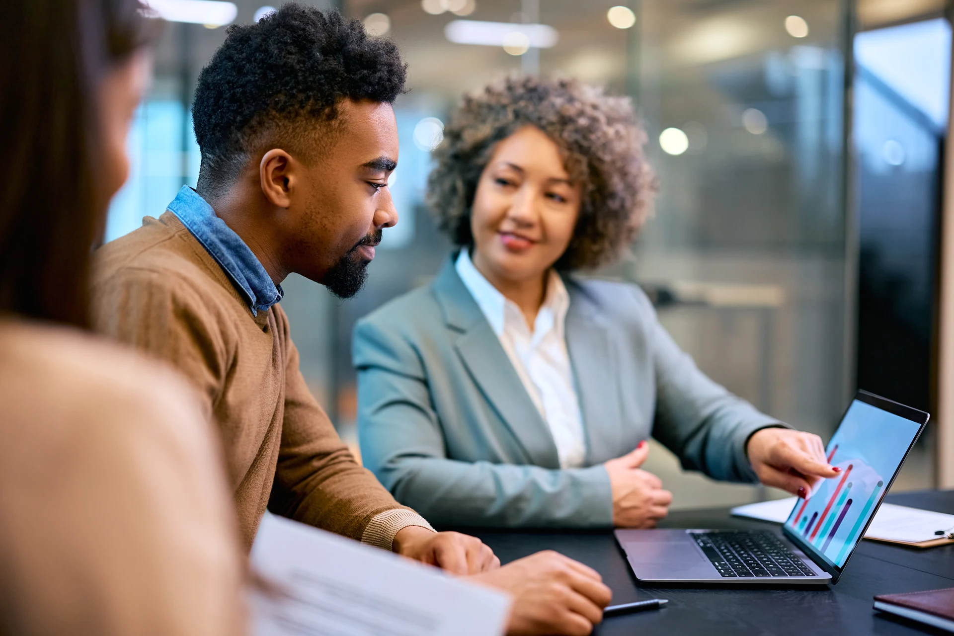 Business professionals discussing cloud-based solutions over a laptop
