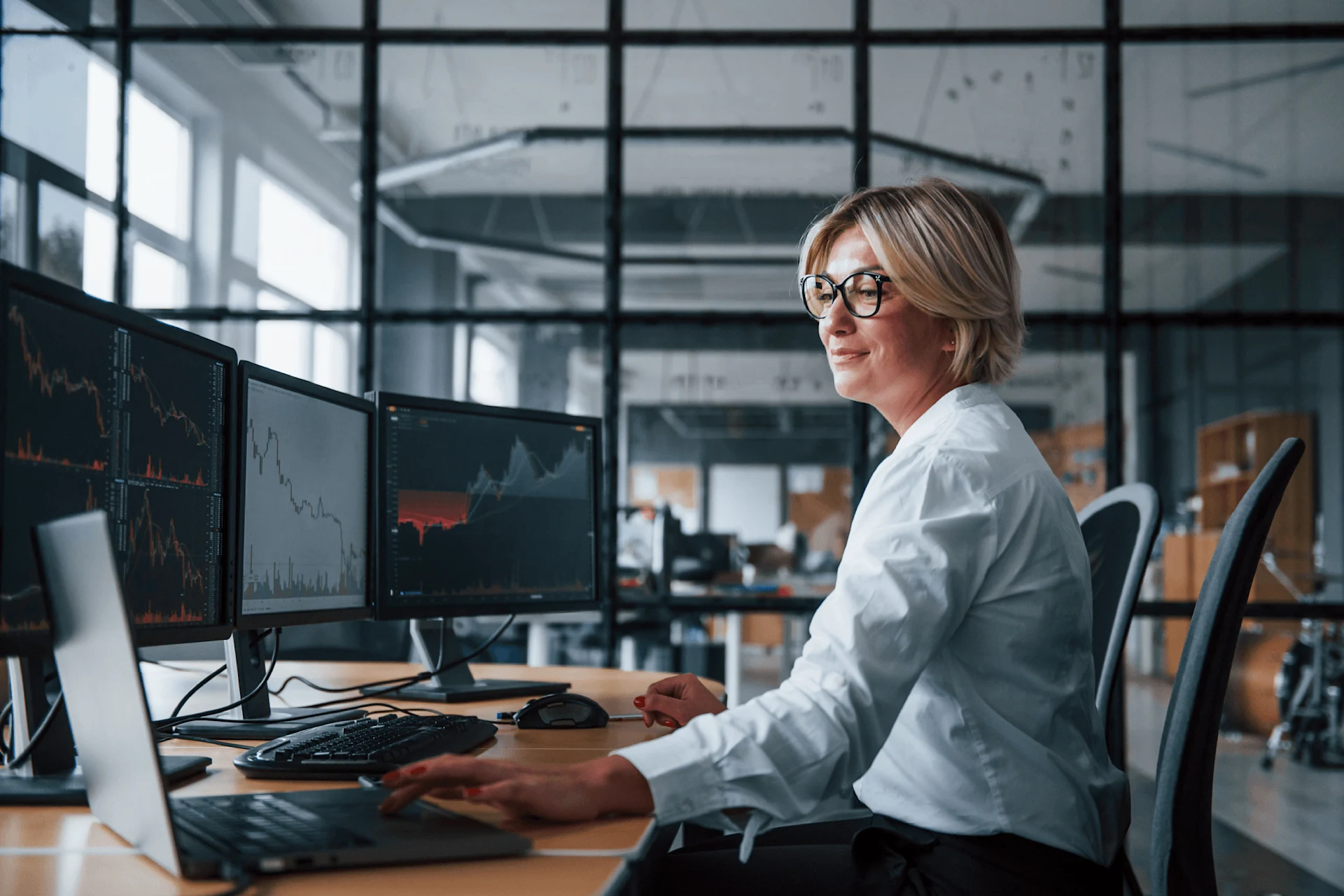 Professional analyzing data on multiple monitors in a modern office