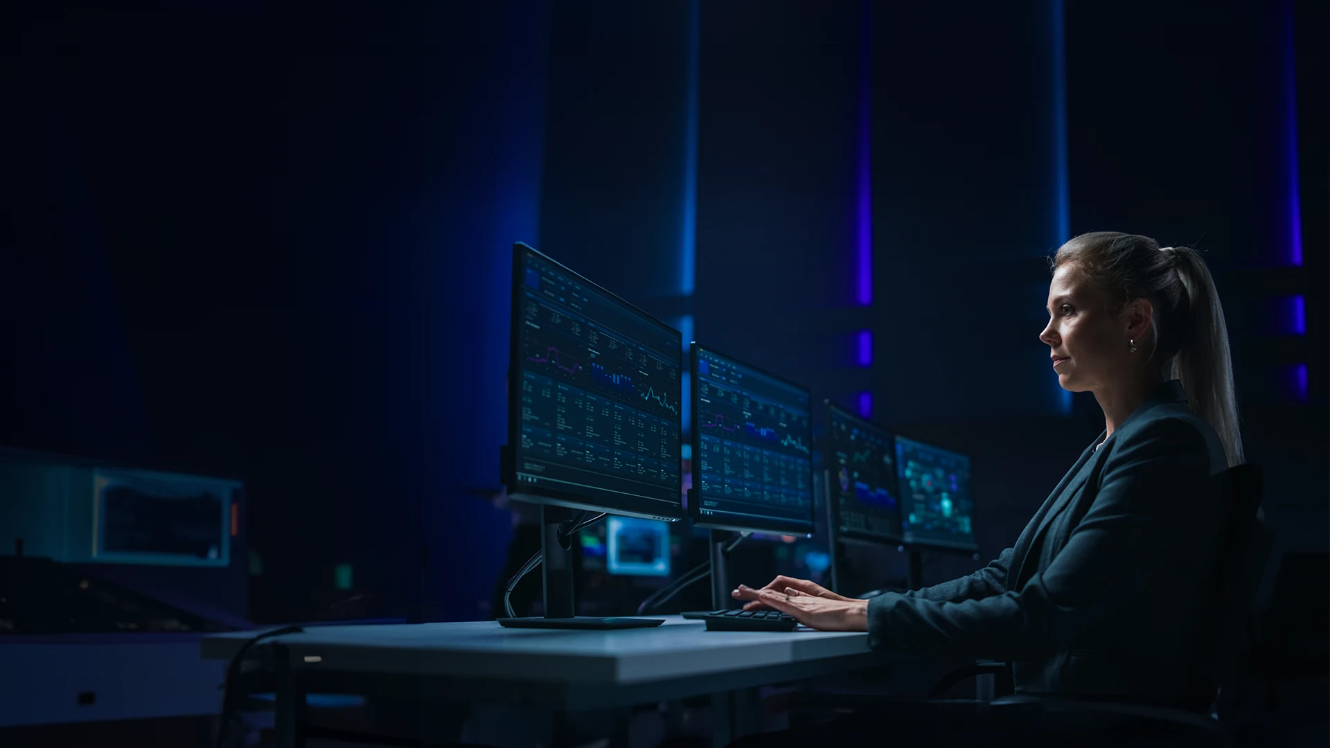 Professional working at a computer with multiple screens analyzing data