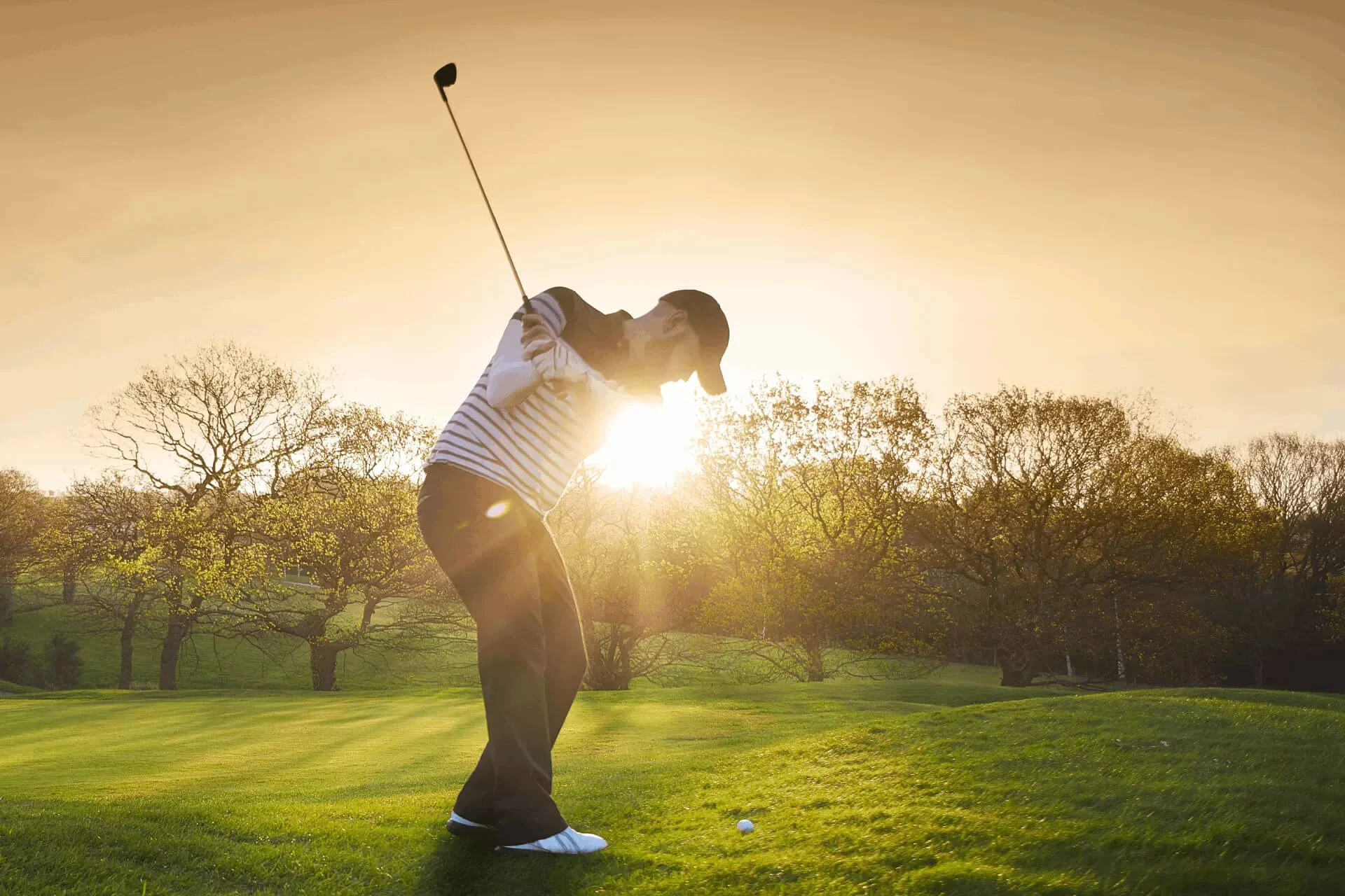 Golfer preparing to swing on a course during sunset