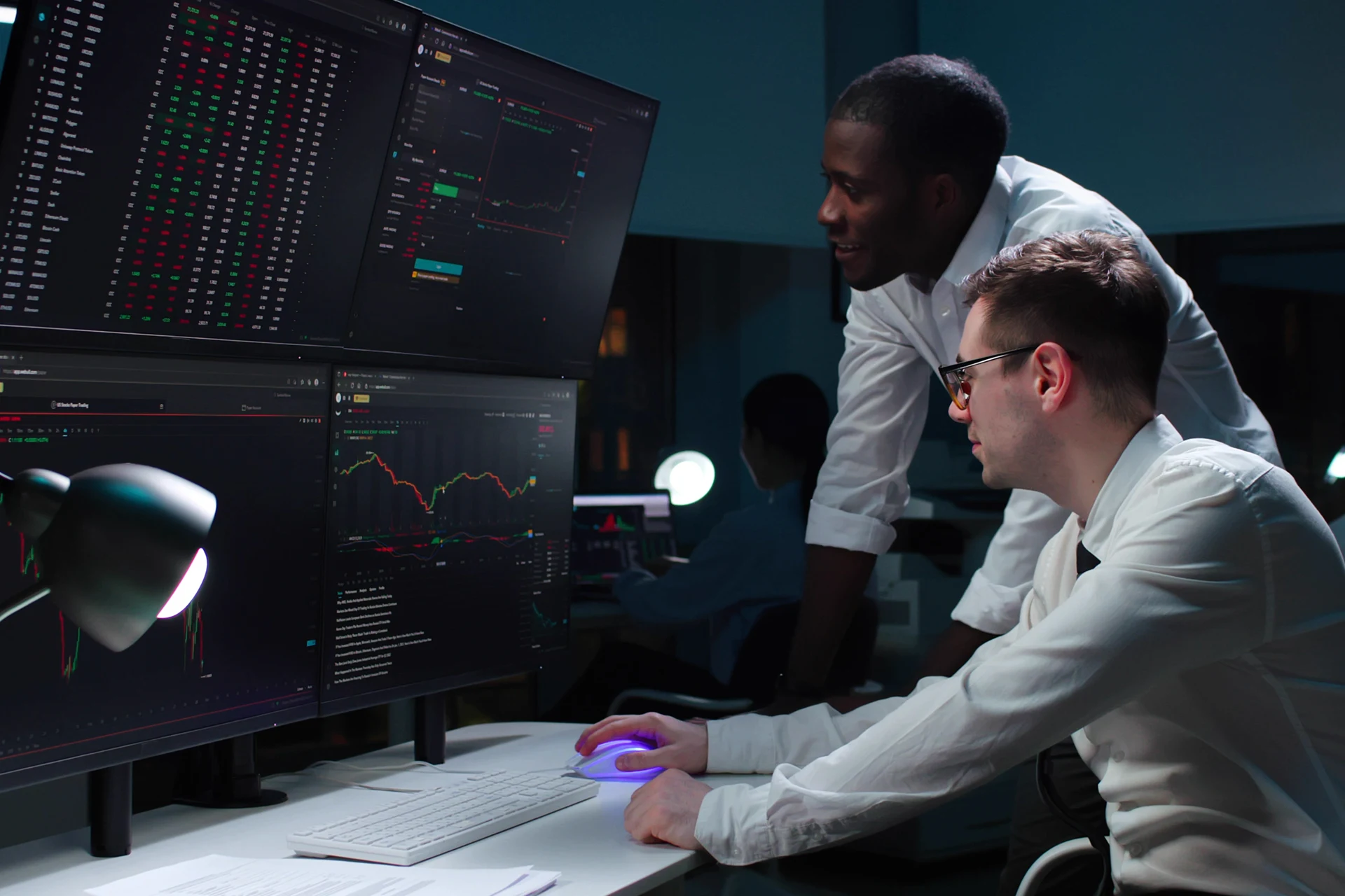 Two professionals analyzing software data on monitors in an office.