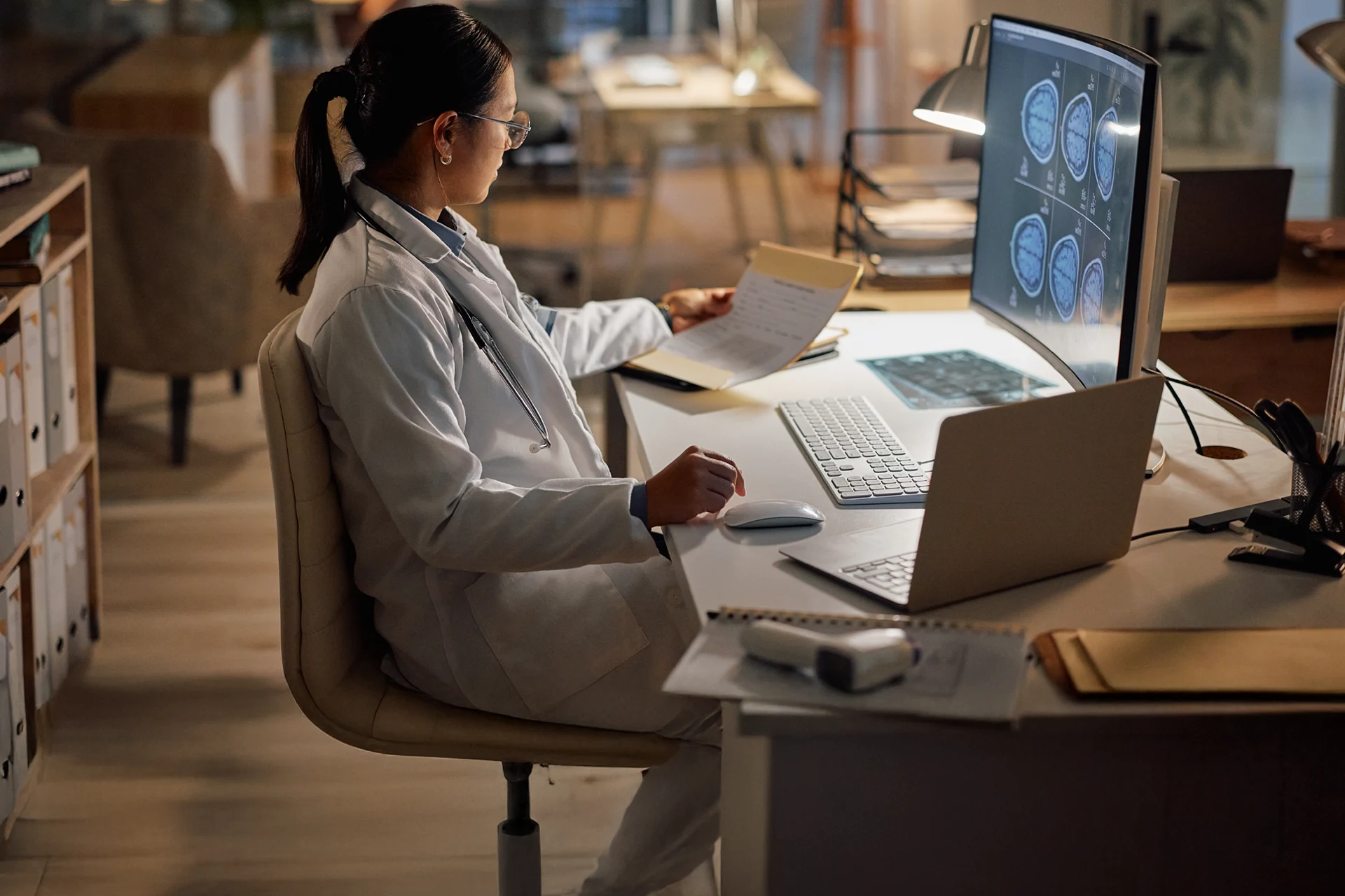Healthcare professional analyzing data on computer while reviewing notes