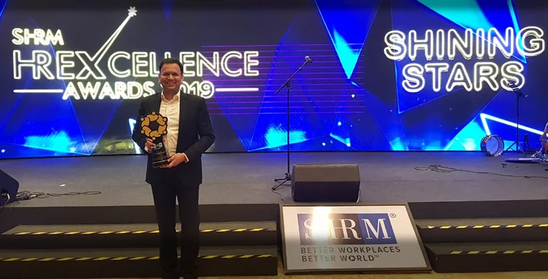 Award winner holding trophy on stage at SHRM HR Excellence Awards 2019