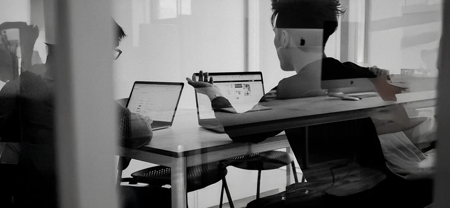 Business professionals collaborating with laptops during an investor discussion