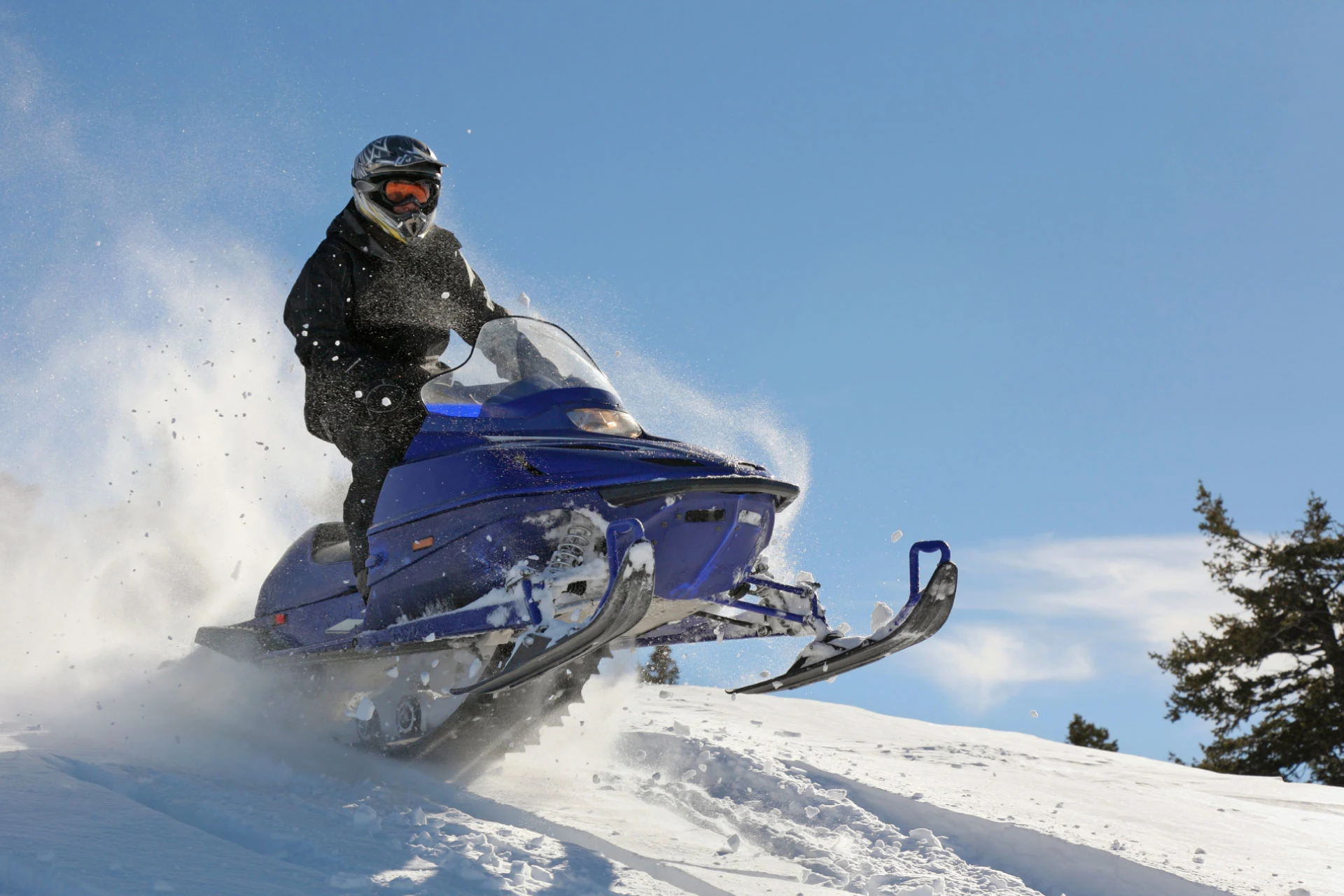 Person riding a blue snowmobile on a snowy landscape