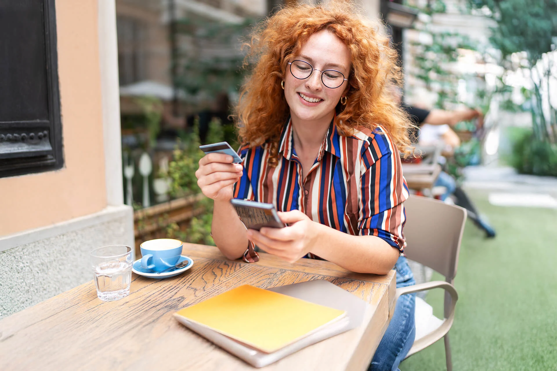 Woman using a smartphone and card at a caf� table with drinks