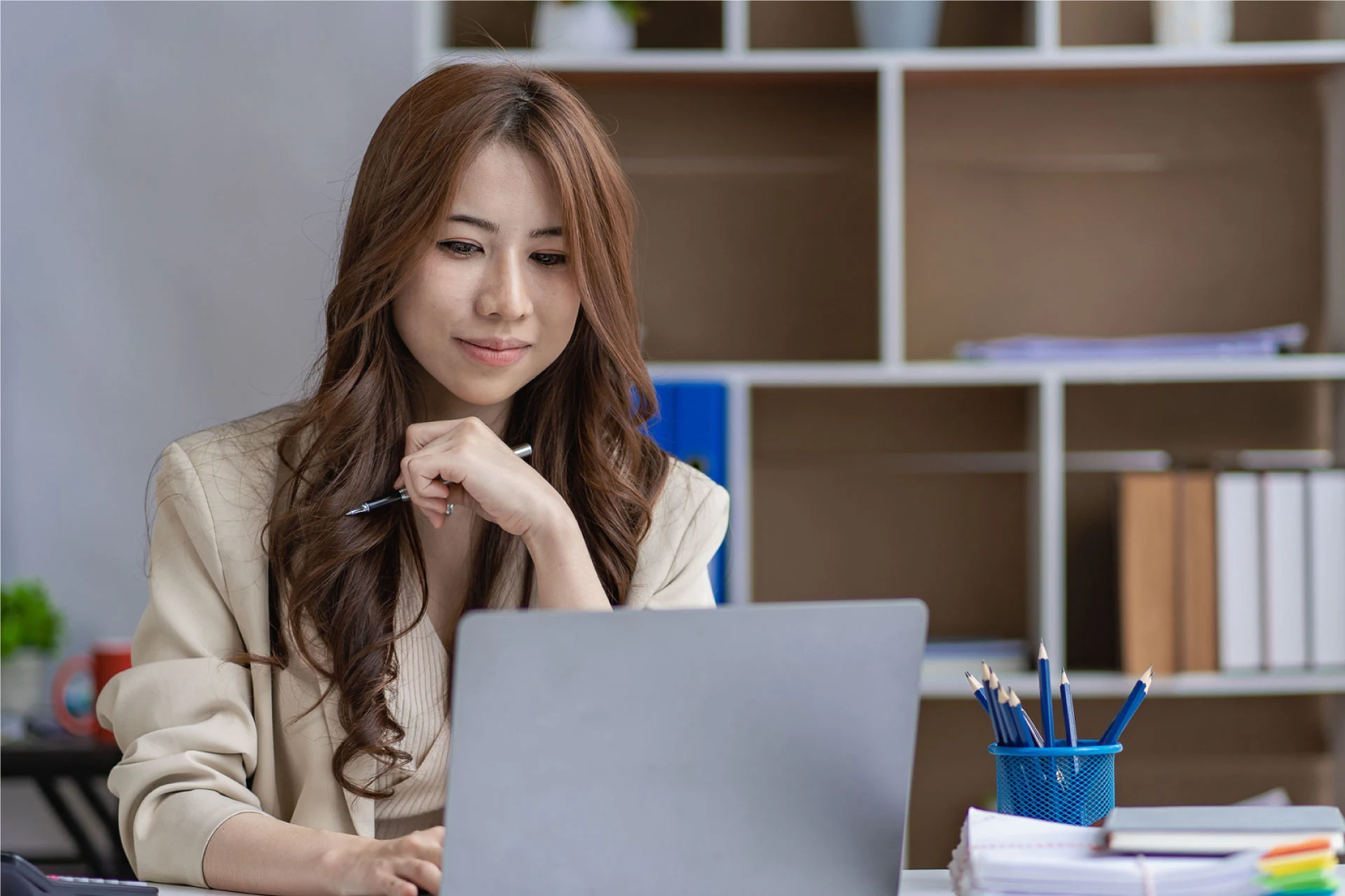 Professional reviewing documents while seated at a desk with a laptop.