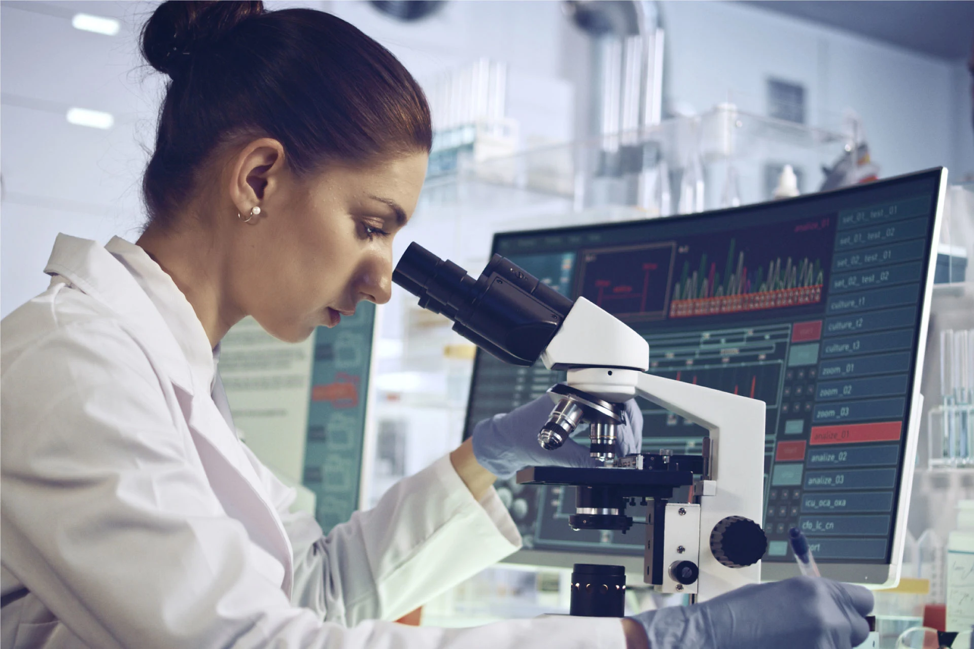 Scientist analyzing data on a computer while using a microscope