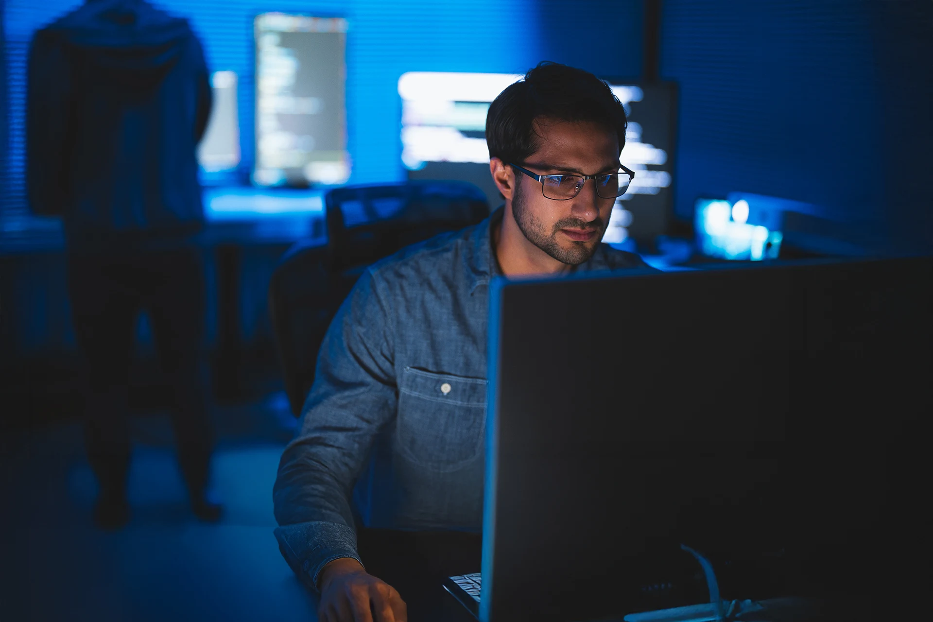 Professional working on a laptop in a dimly lit office environment
