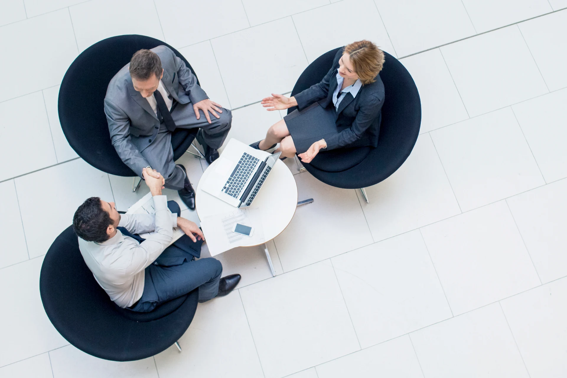 Three business professionals discussing Guidewire program specs over laptop