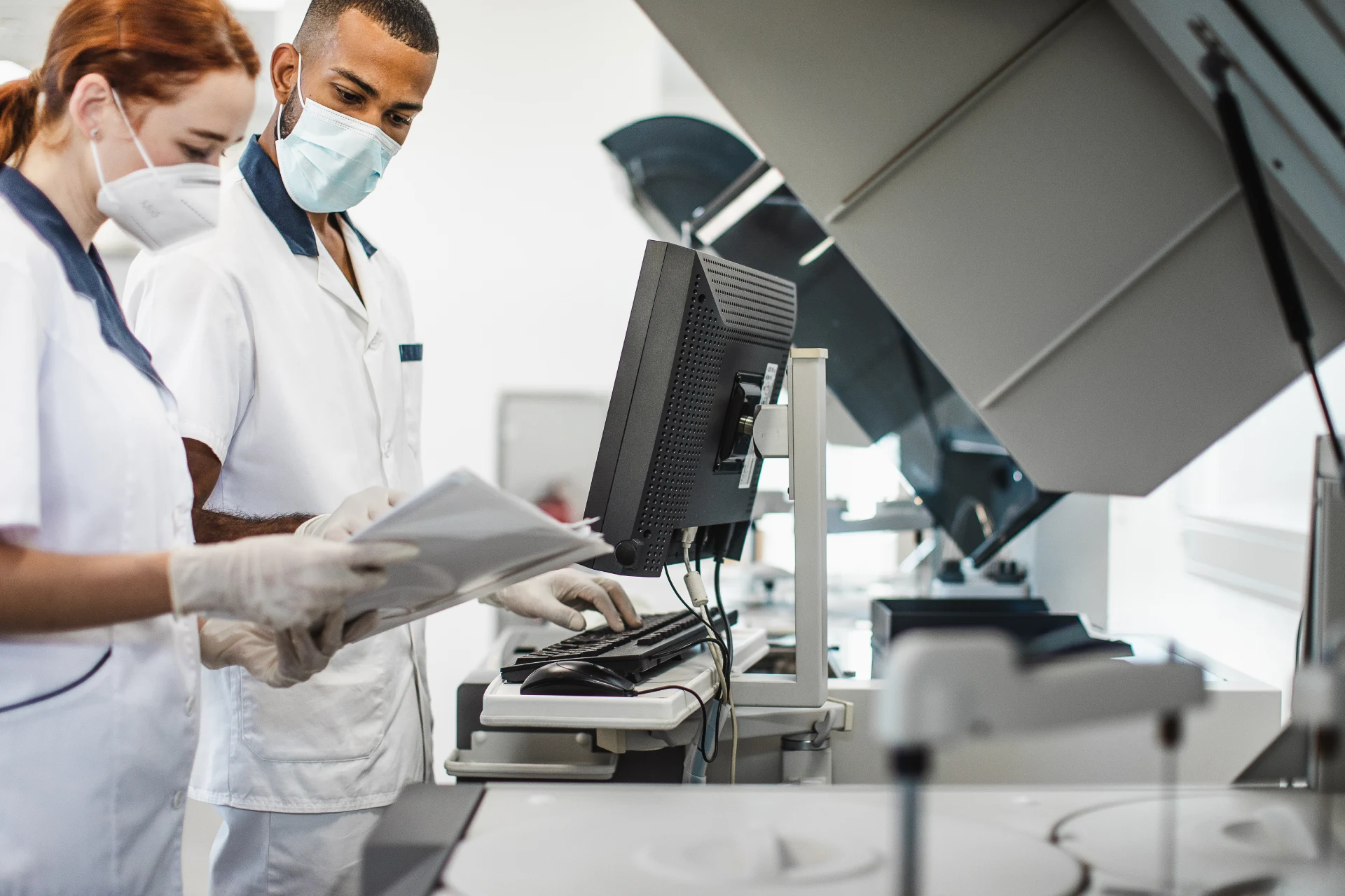 Two healthcare professionals reviewing documents near a computer setup