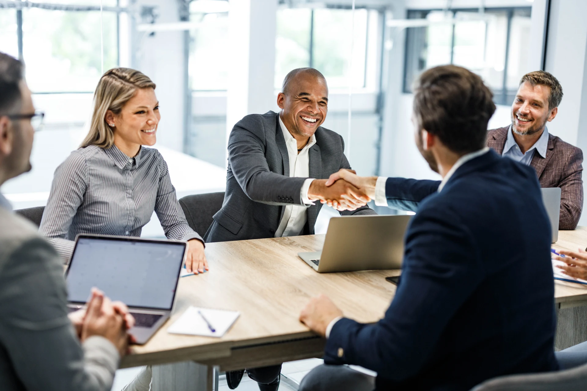 Two professionals shaking hands during a business meeting about migration.