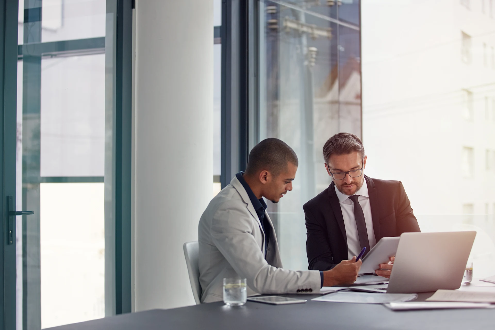 Two professionals discussing a tablet during a business meeting