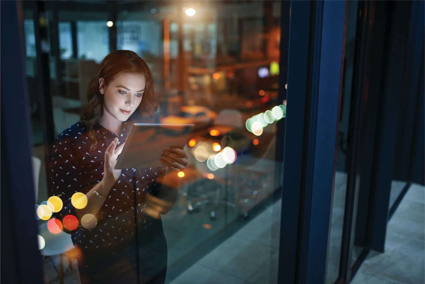 Person using a tablet while looking through a window at night