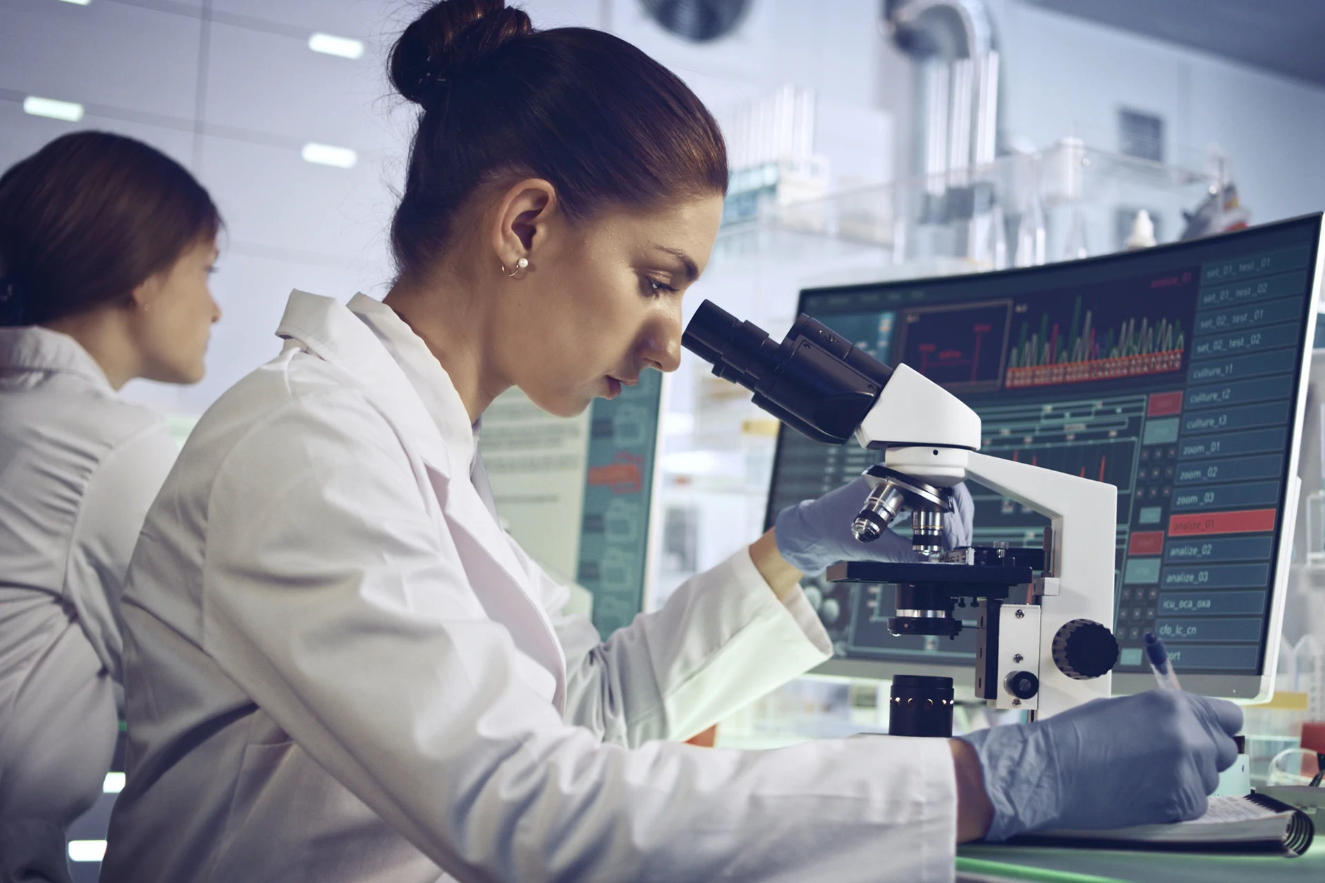 Scientist examining samples under a microscope in a diagnostic lab