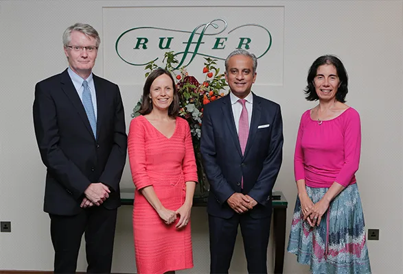 Four professionals posing in front of Ruffer corporate branding signage UK