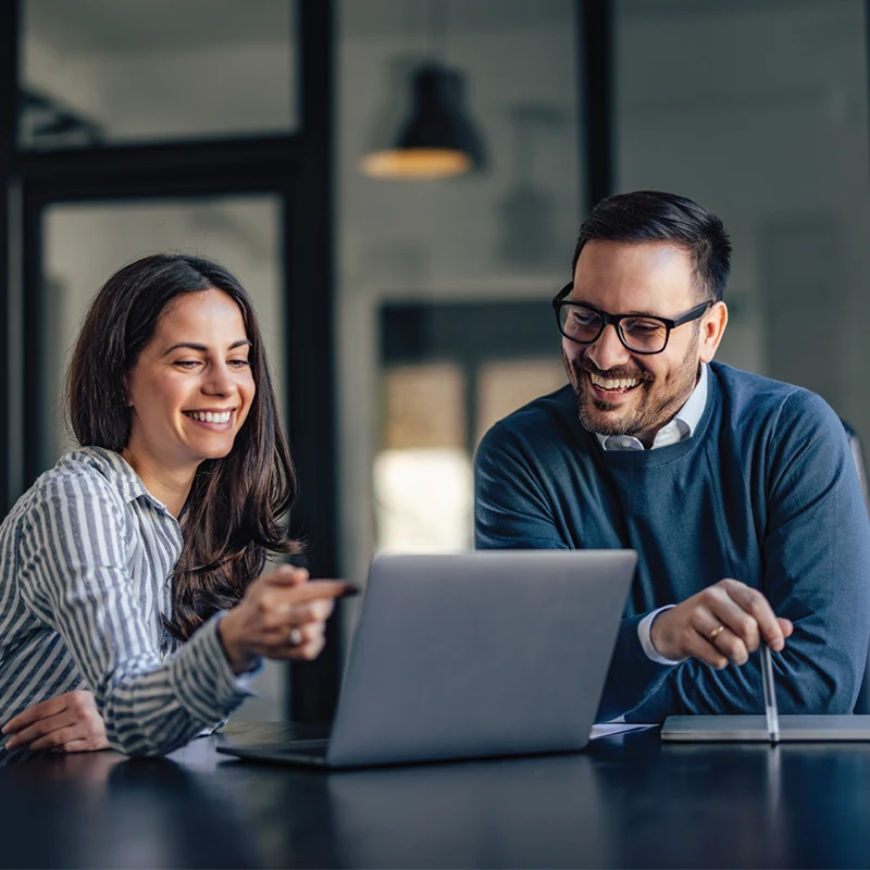 Two professionals discussing IT modernization strategy over a laptop.