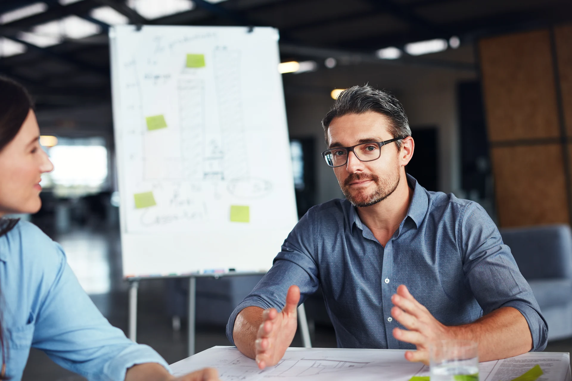 Two professionals discussing strategies at a meeting table with notes.