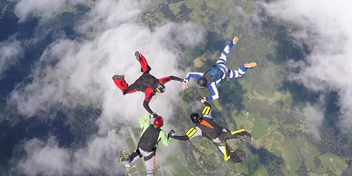 Skydivers performing formation jump over green landscape for Oracle Cloud MSP