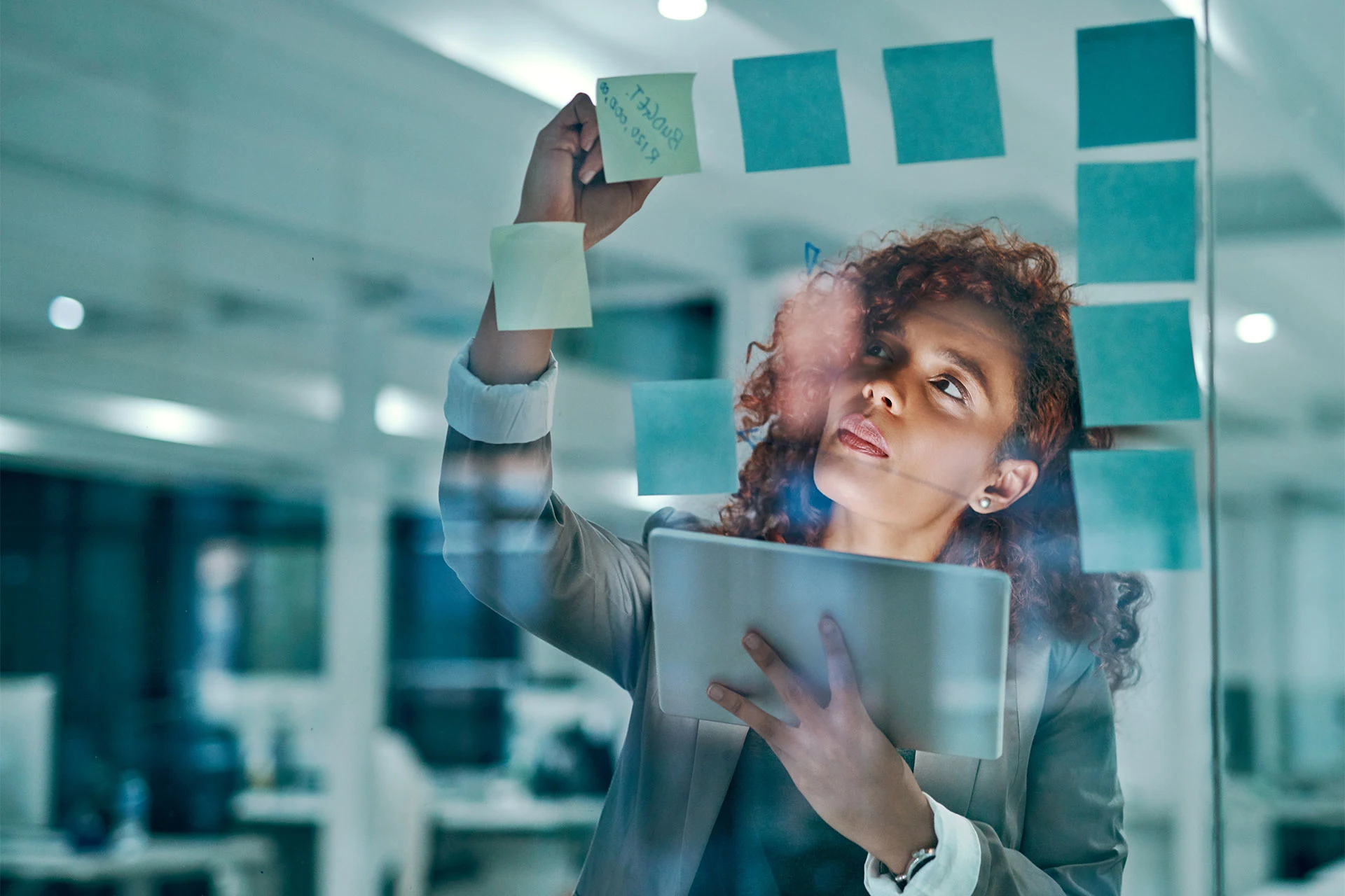 Professional placing sticky notes on a glass wall in an office setting