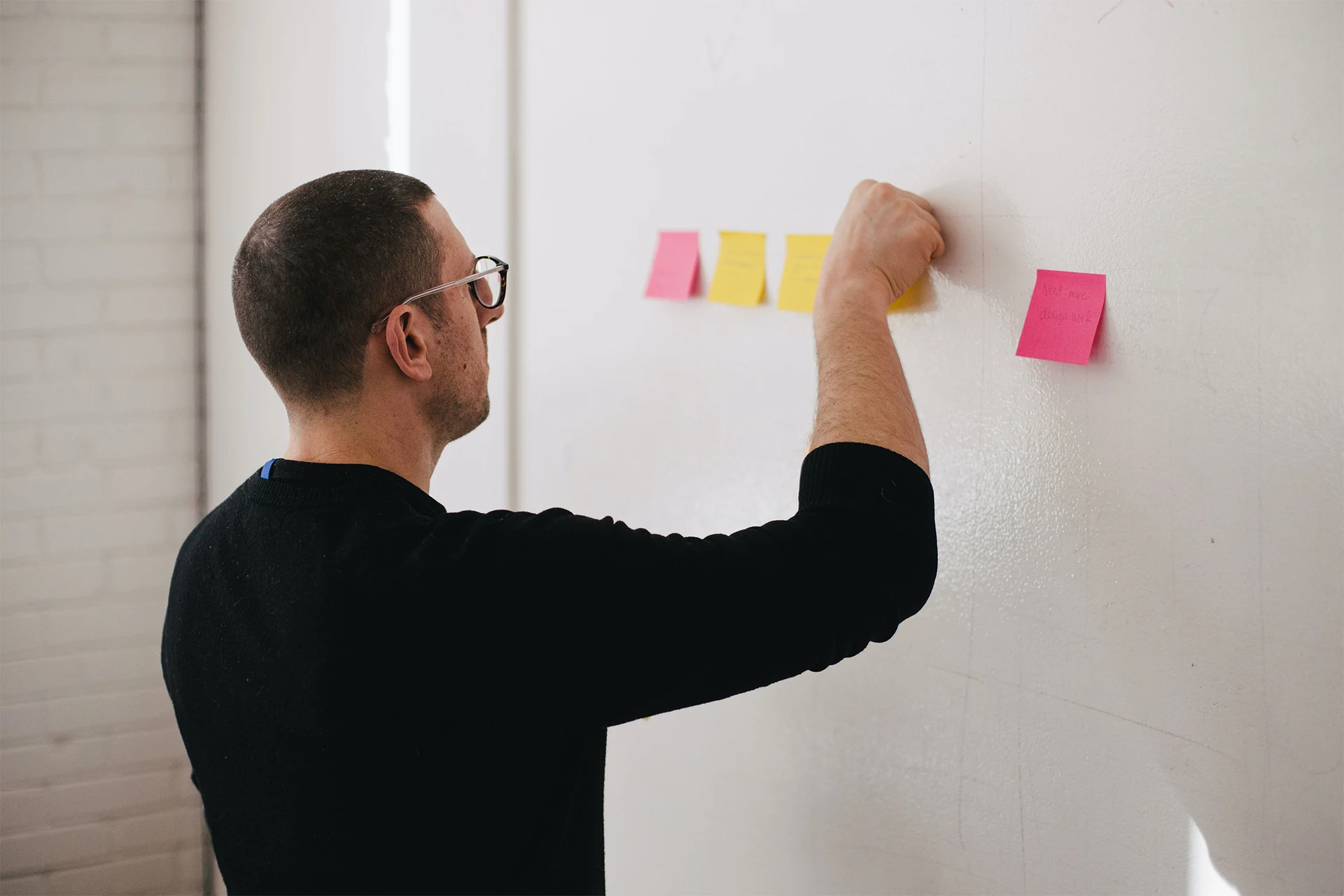 Person placing sticky notes on a wall during a design research session.