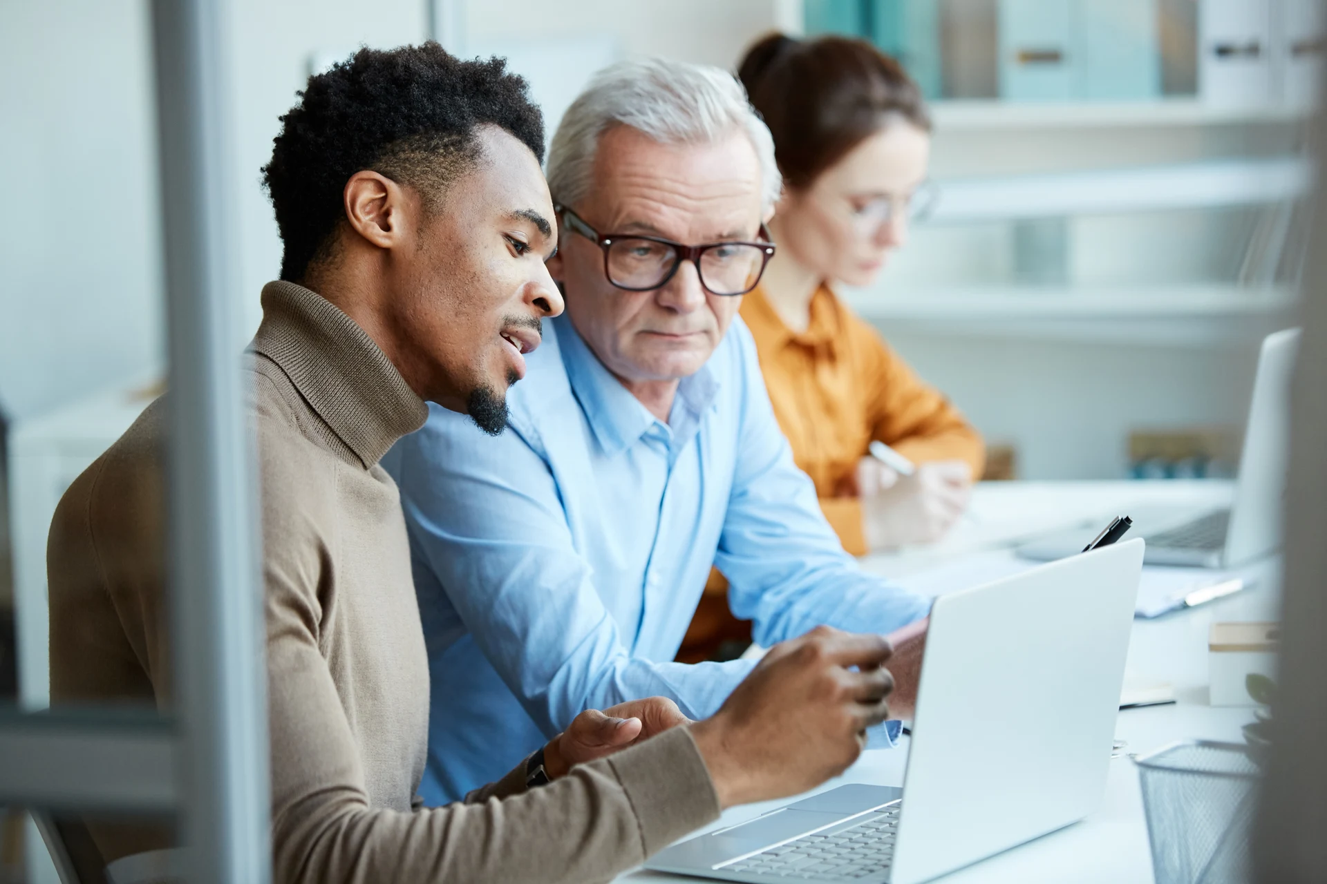 Three professionals collaborating at a laptop in a business environment