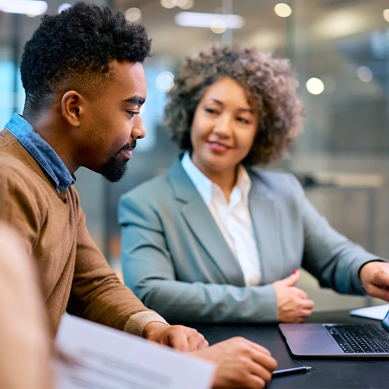 Business professionals discussing cloud-based solutions over a laptop