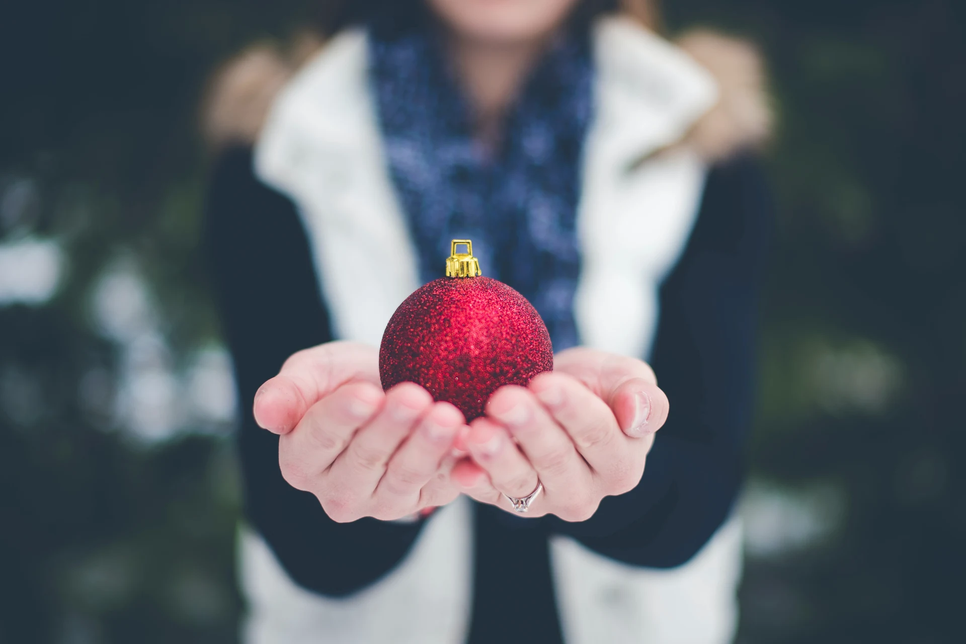 Person holding a red Christmas ornament for holiday readiness