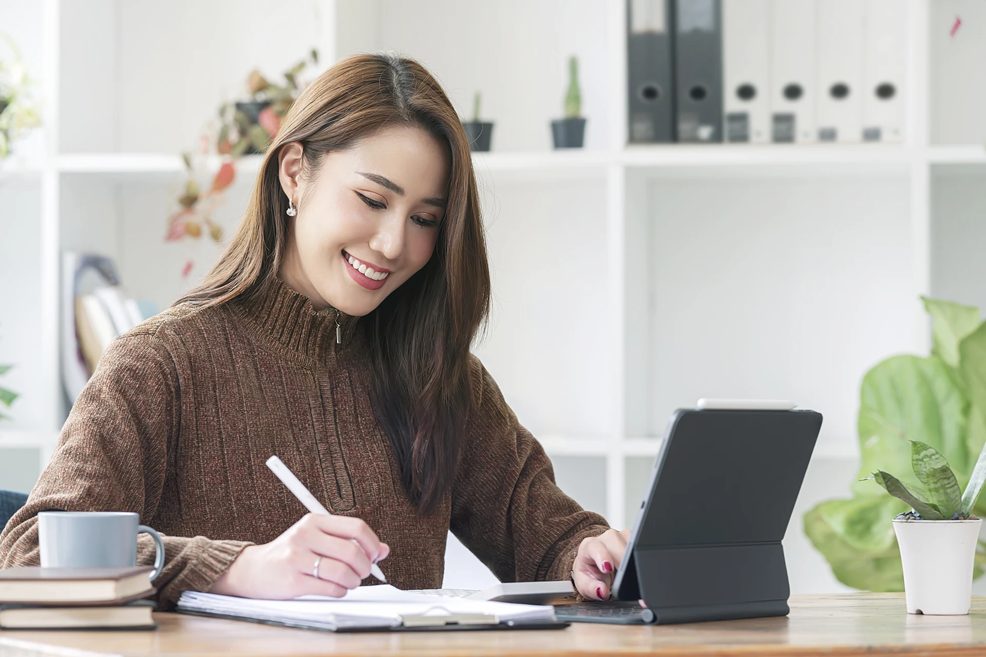 Woman writing notes on a tablet in a modern office environment