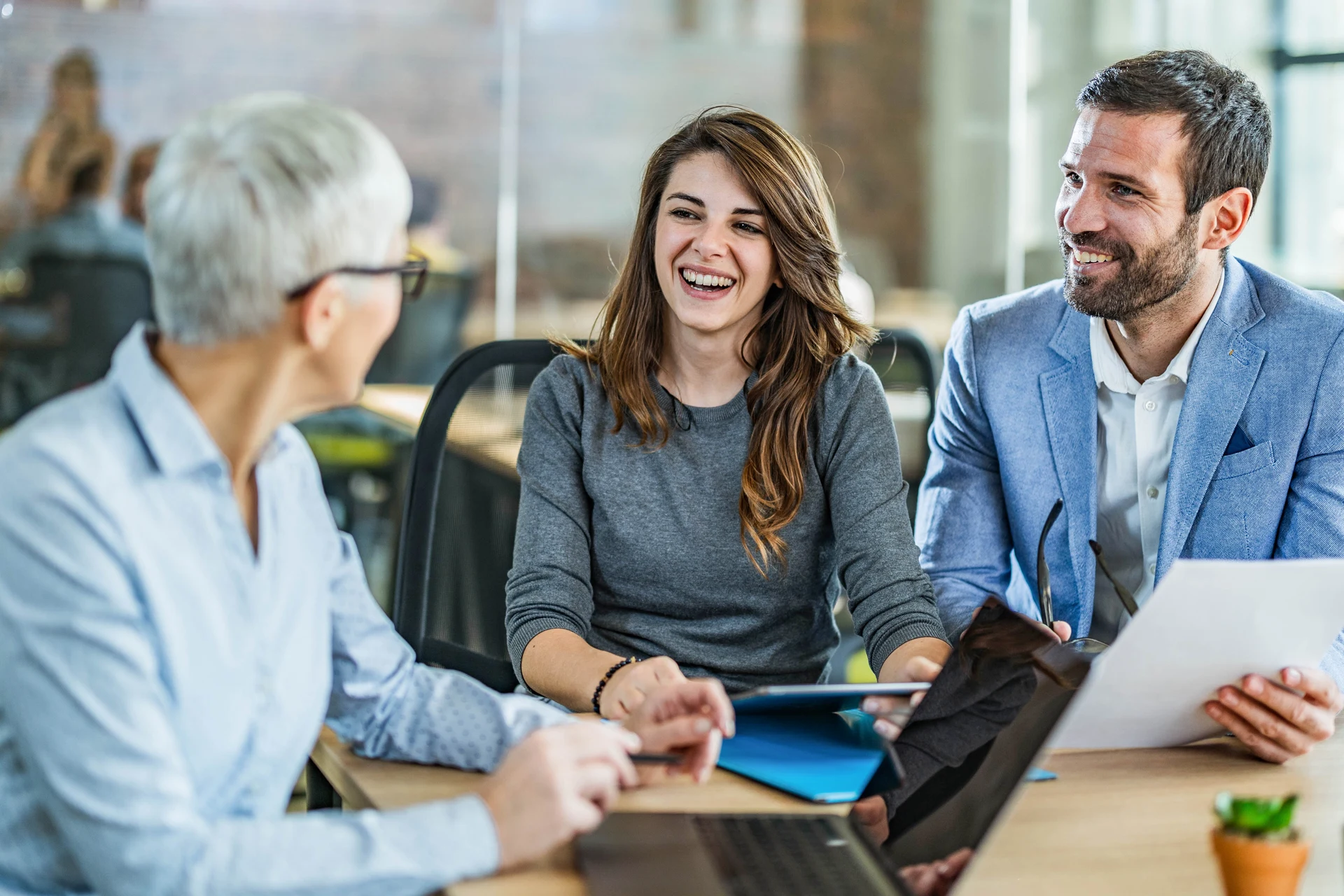 Three professionals engaged in a discussion around a conference table.