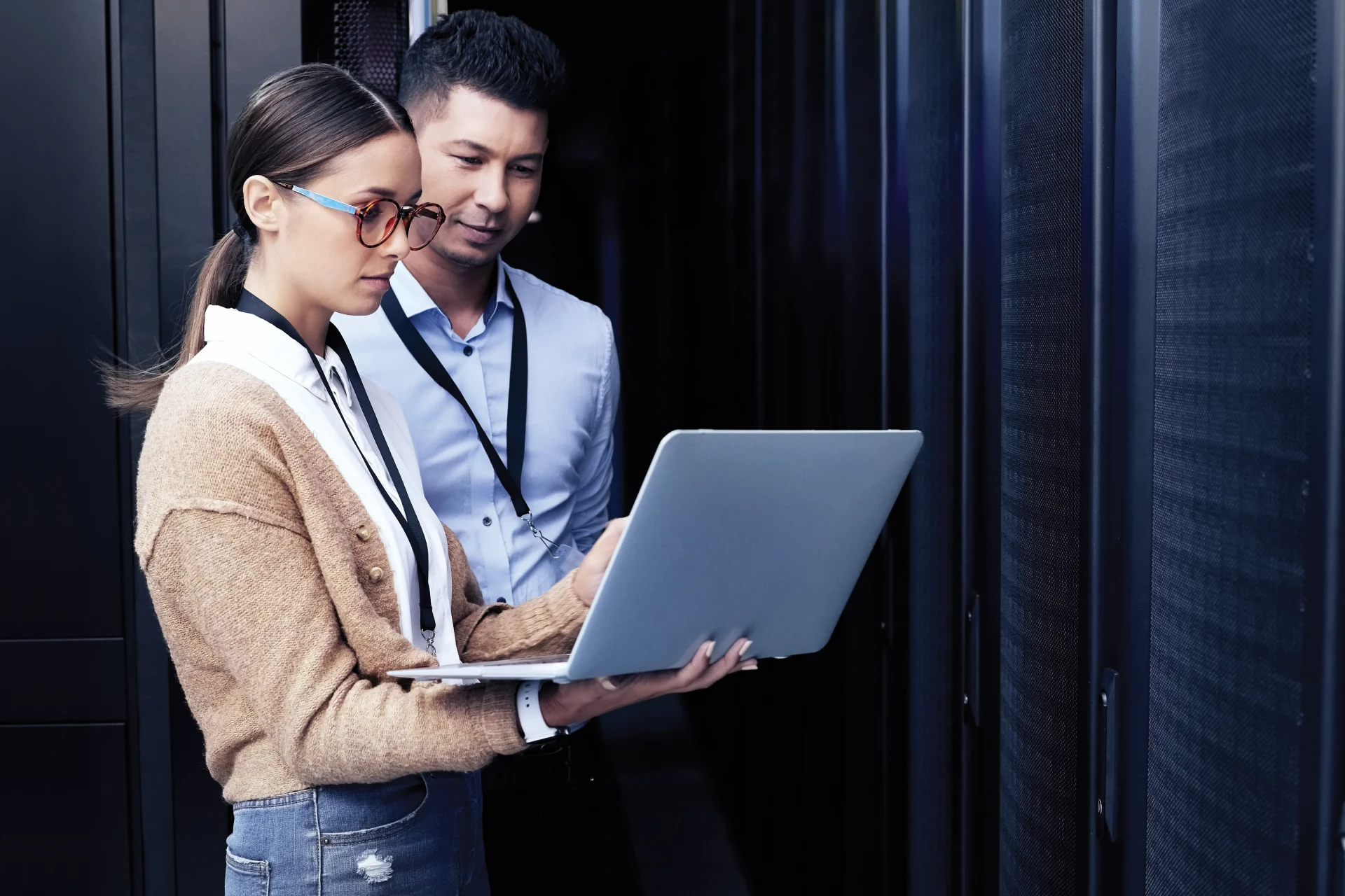 Two professionals analyzing data on a laptop in a server room