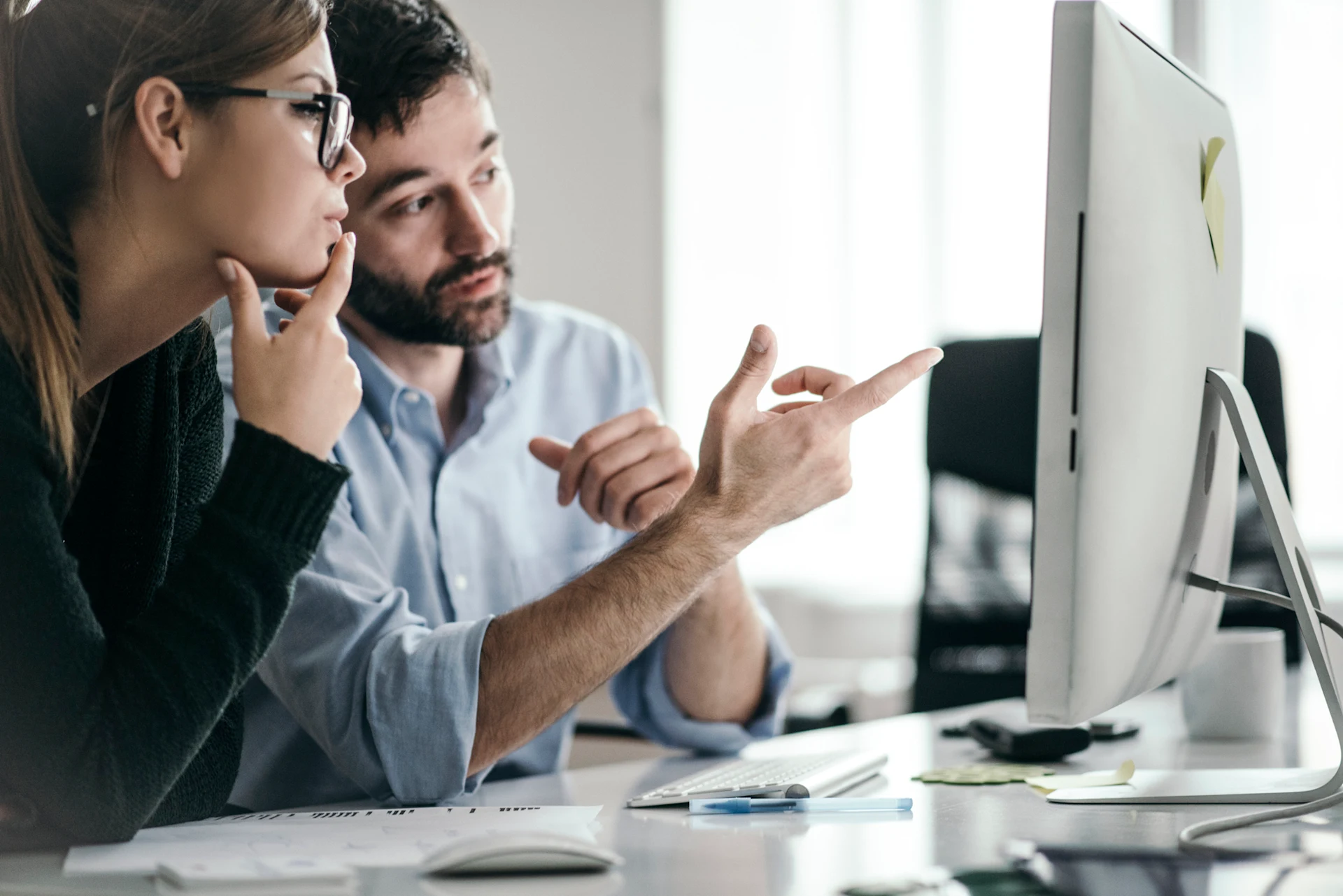 Two professionals discussing partner performance metrics at a computer