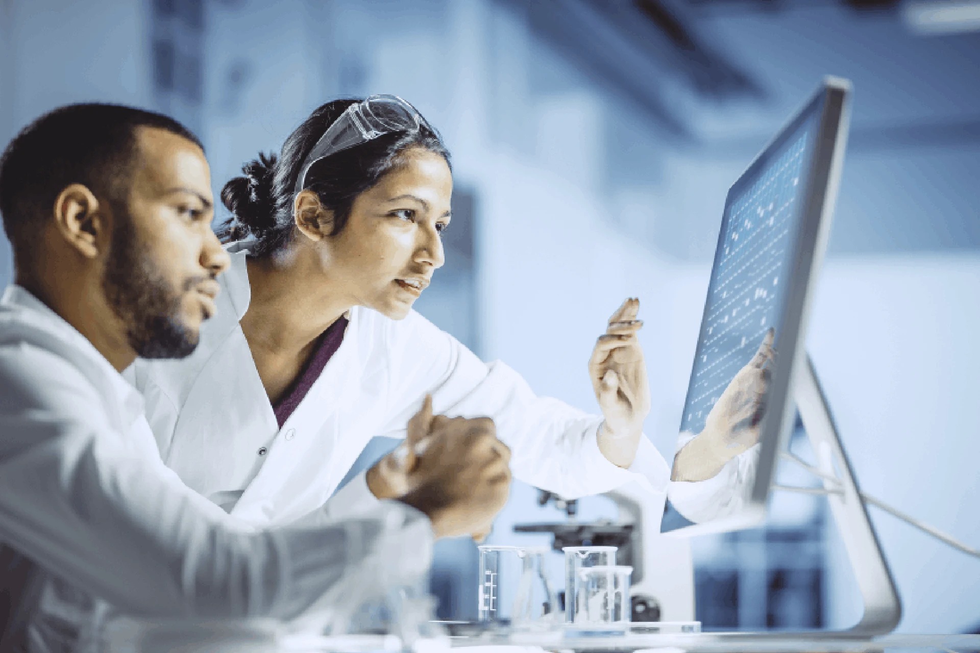 Two professionals discussing data on a computer in a laboratory setting.