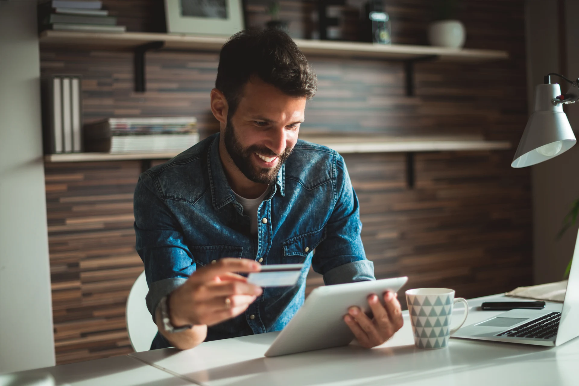 Person holding a credit card and tablet in a modern workspace