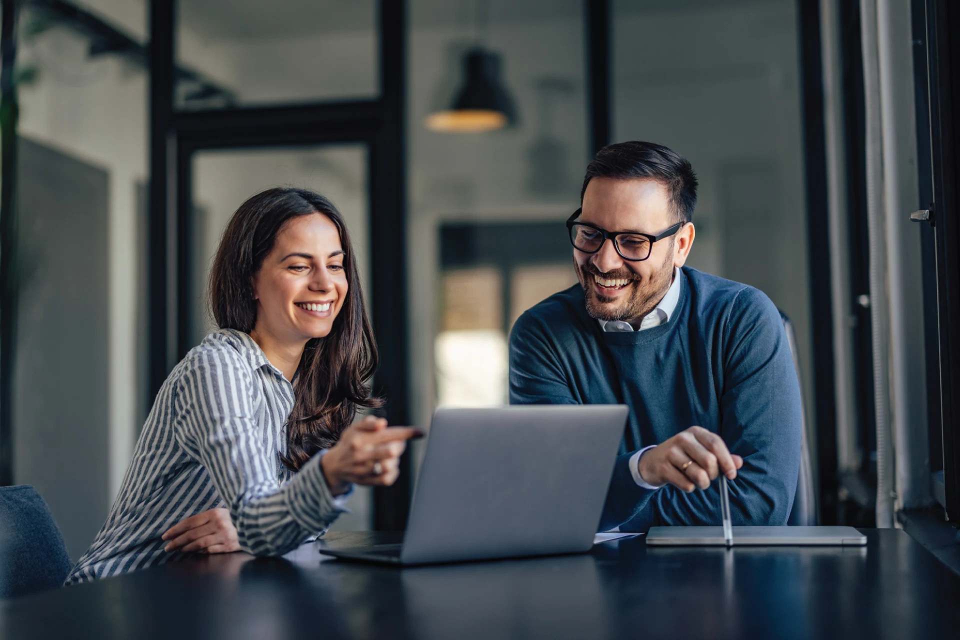 Two professionals discussing IT modernization strategy over a laptop.