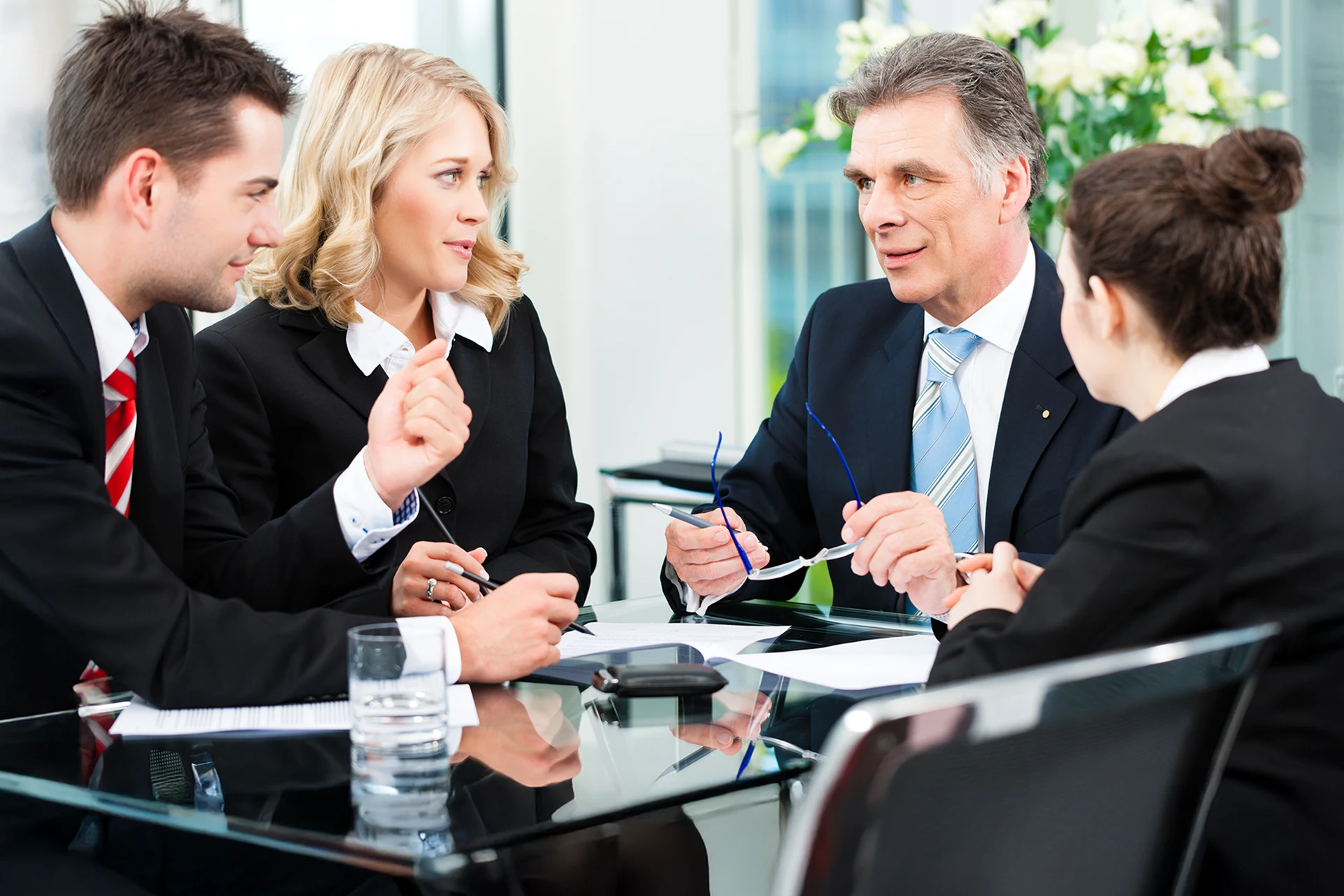 Business meeting with four professionals discussing at a conference table.