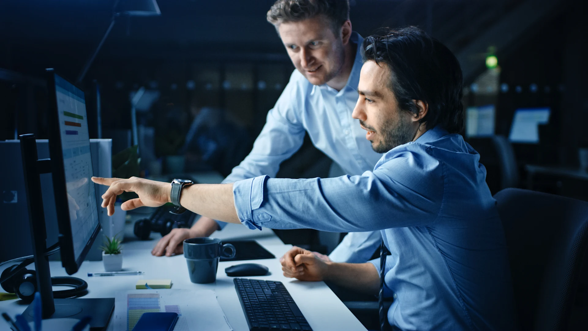 Two professionals collaborating at a computer in a modern office setting.