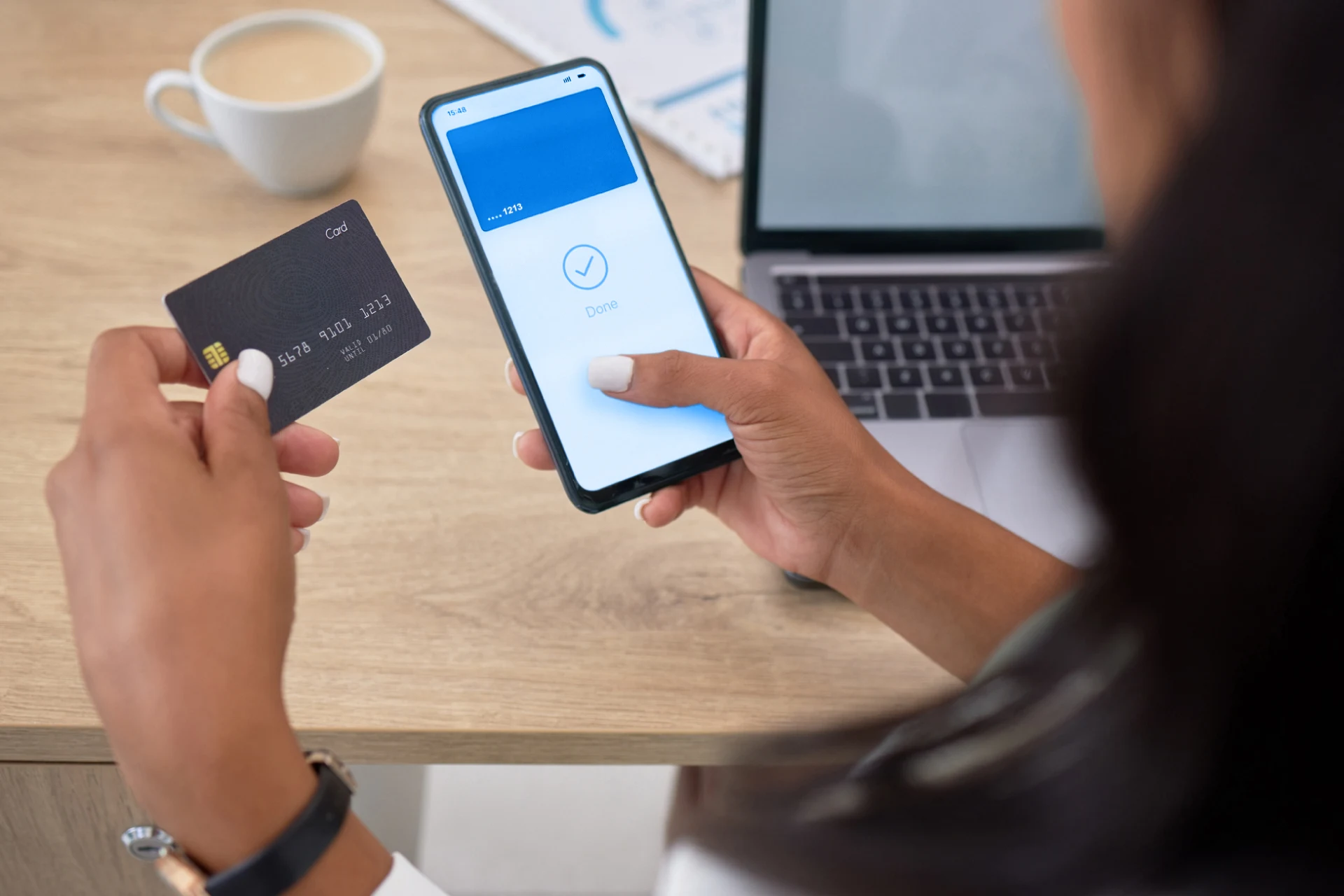 Person using a phone to process a card transaction at a workspace.