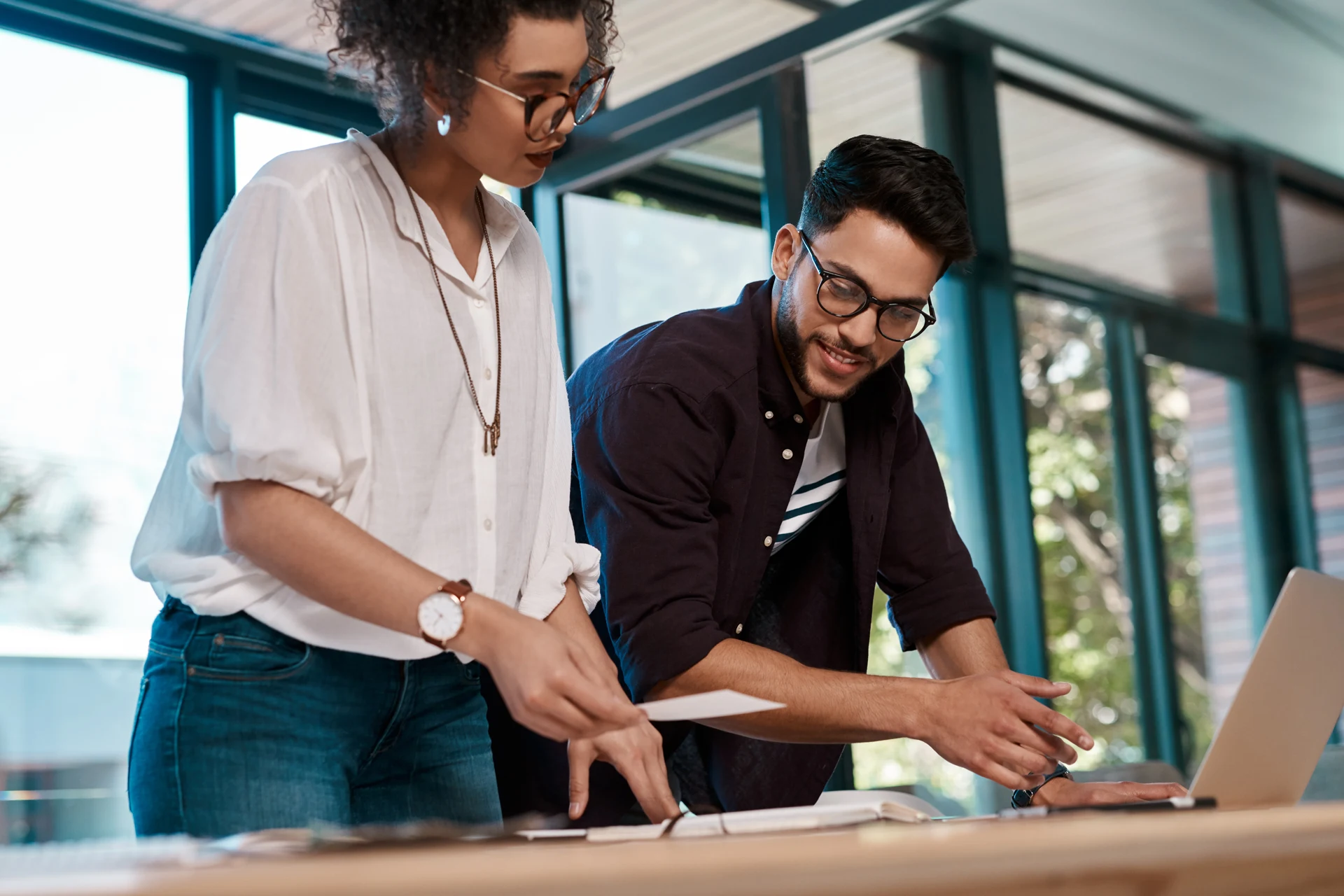Two professionals discussing documents in a collaborative workspace