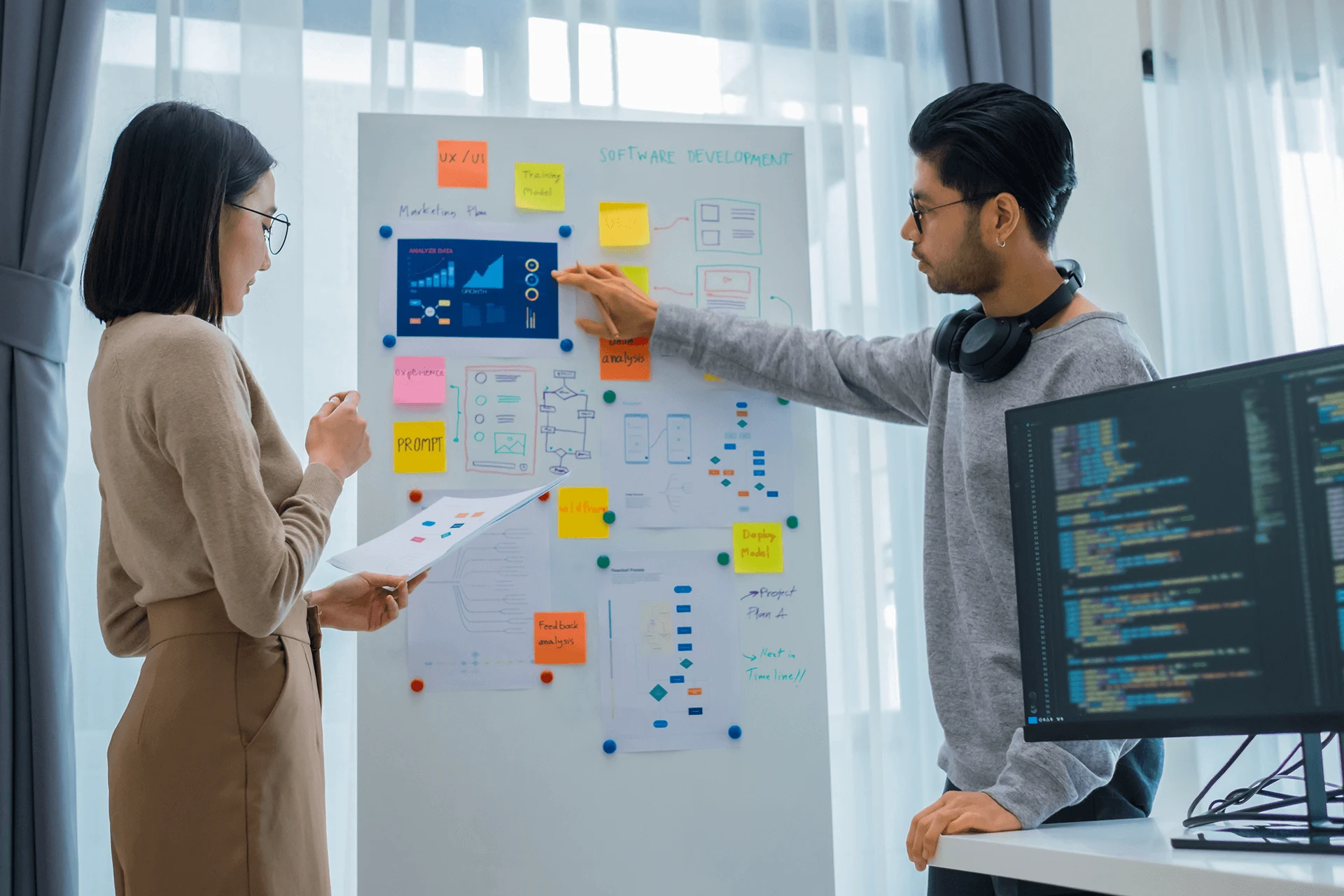 Two professionals discussing software development using visual aids.