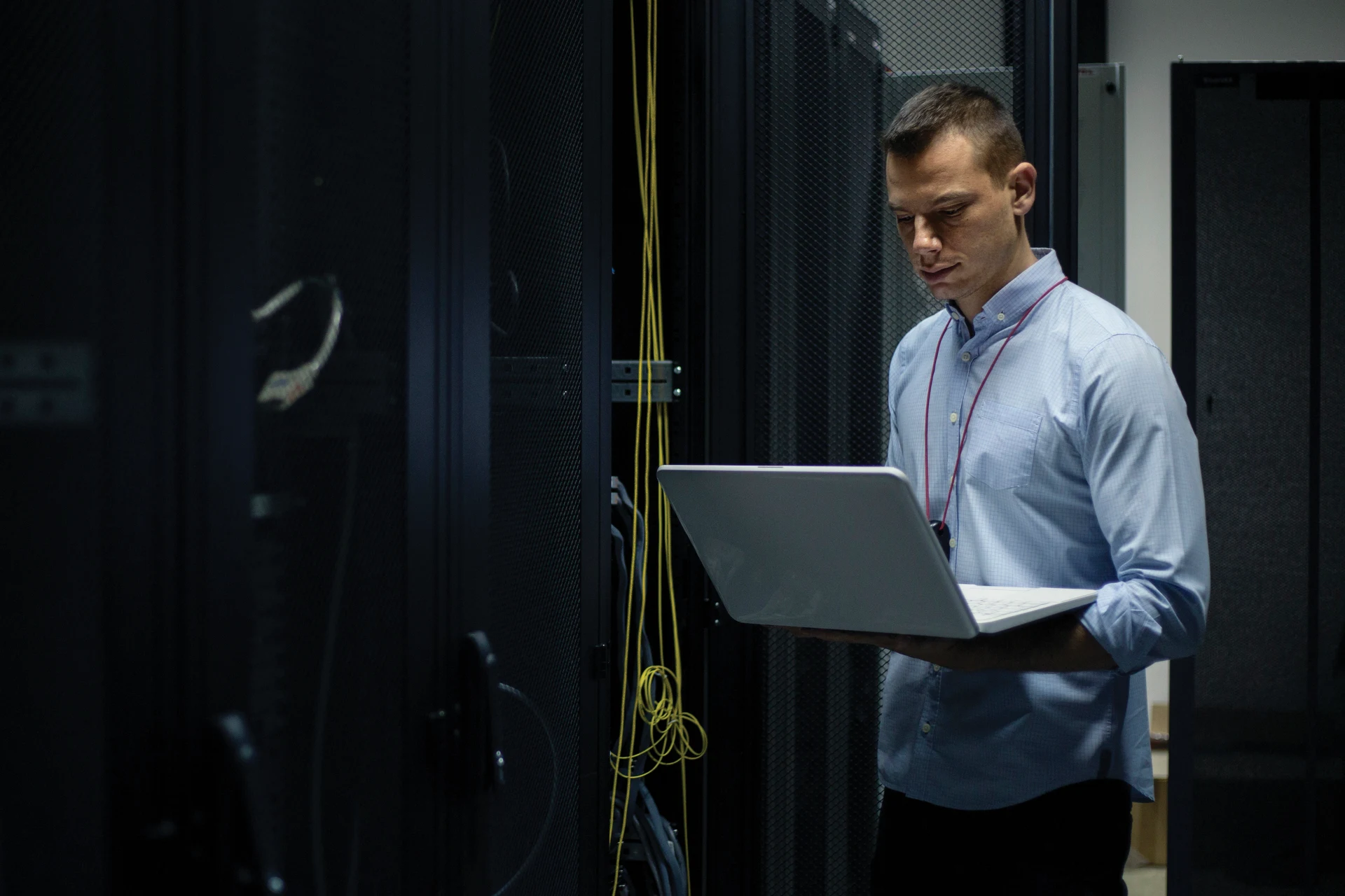 Professional working on a laptop in a server room for digital infrastructure